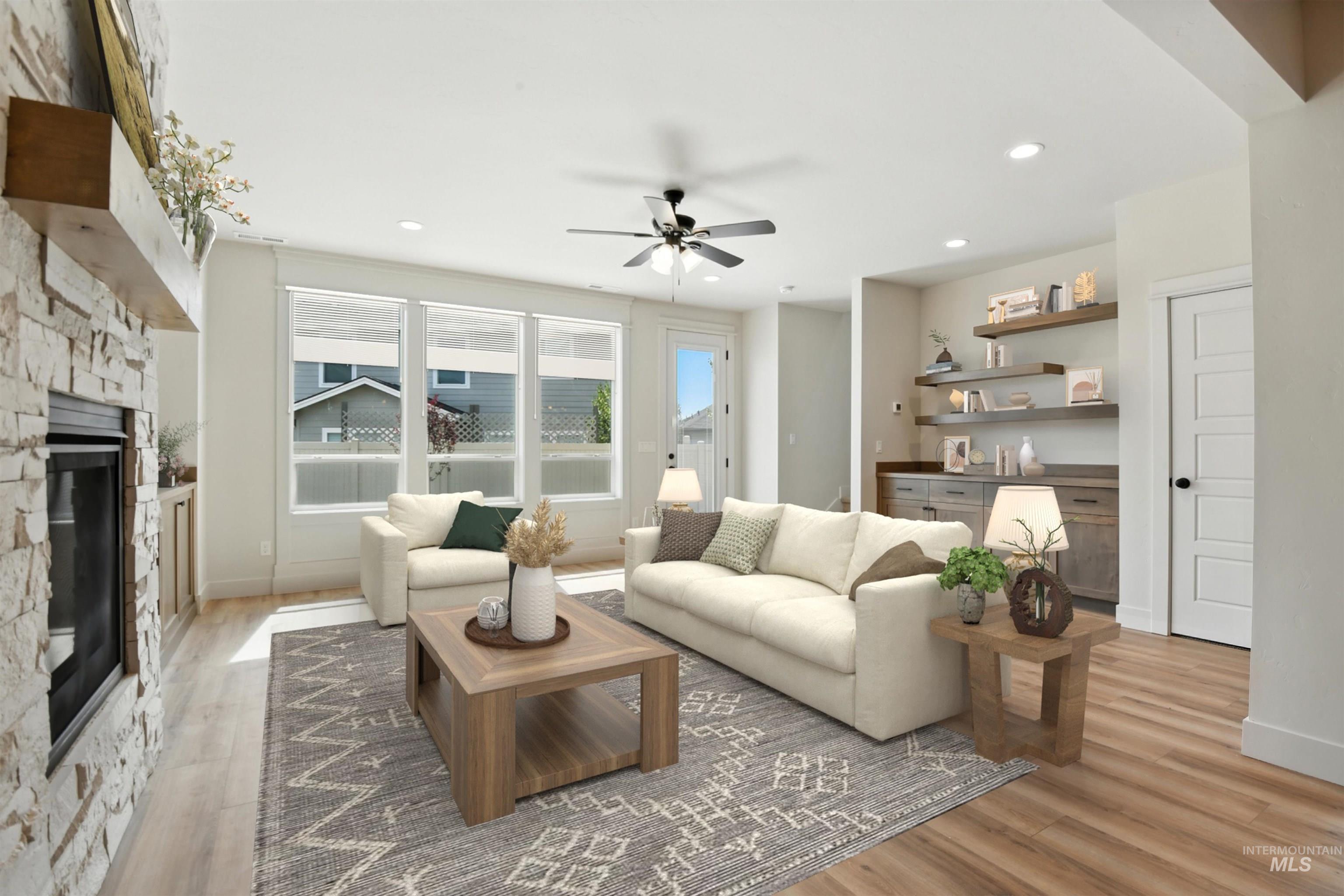 Living area with a stone fireplace, a ceiling fan, light wood-style floors, and recessed lighting