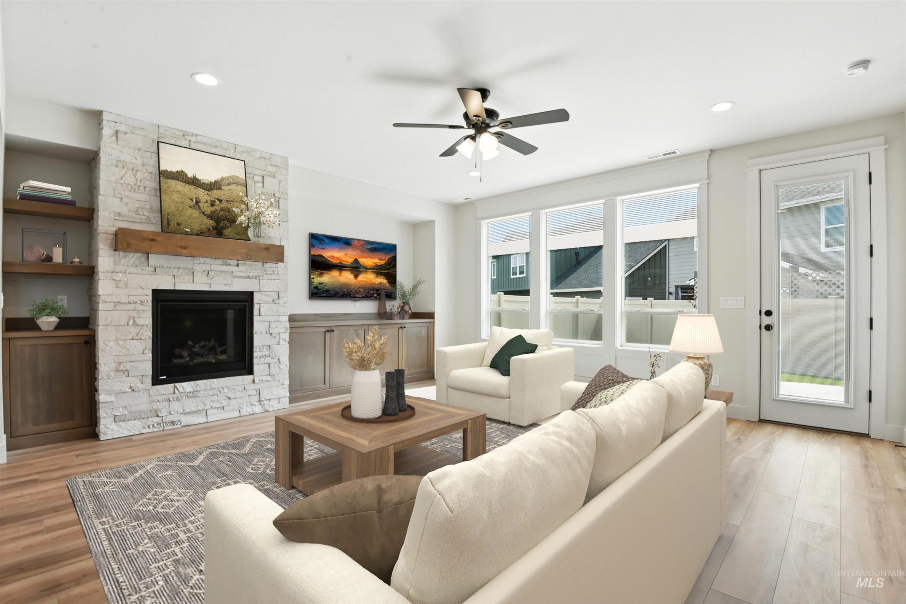 Living area featuring light wood-style floors, a ceiling fan, a stone fireplace, and recessed lighting
