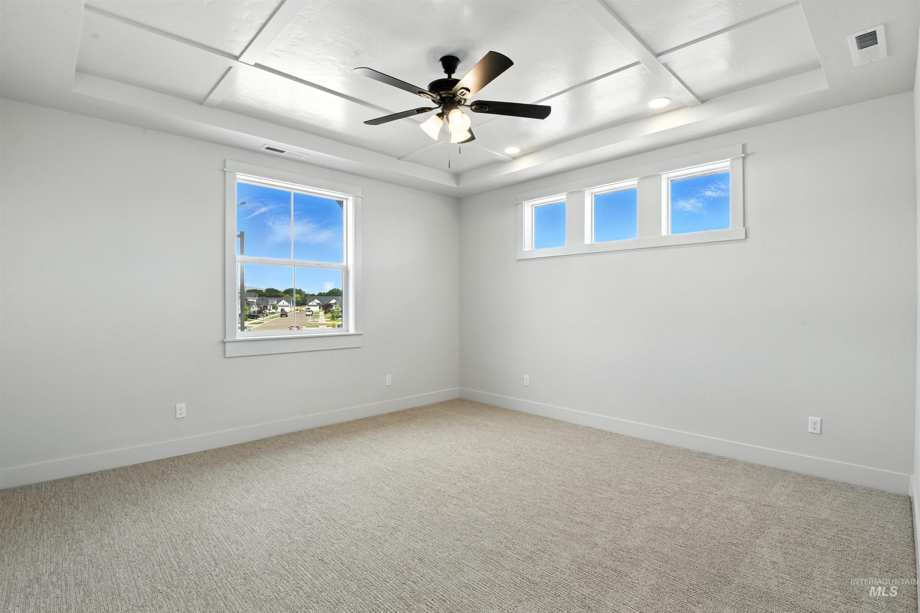 Empty room featuring a raised ceiling, a ceiling fan, light colored carpet, and recessed lighting
