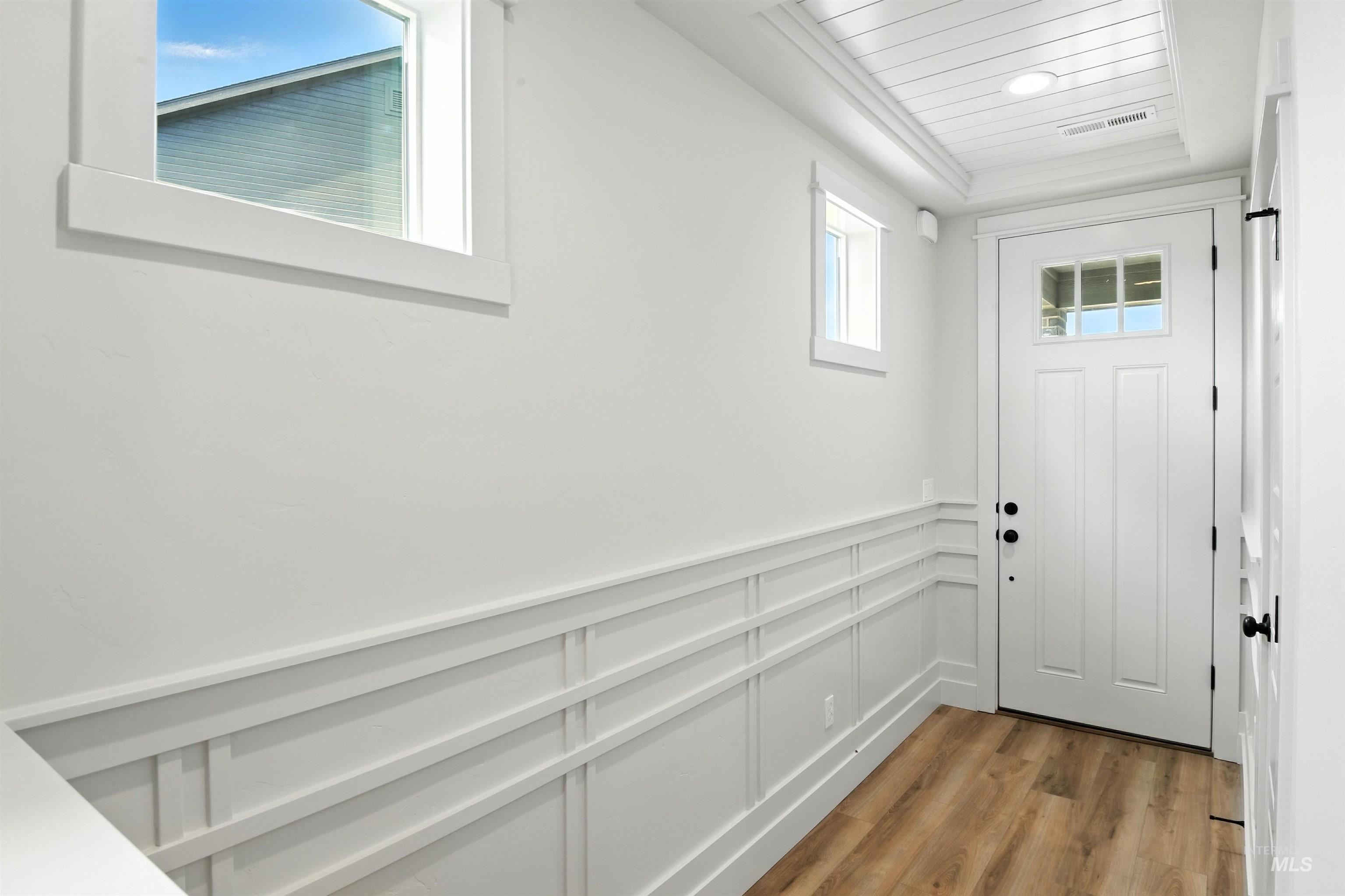Doorway to outside with light wood-style flooring and a wainscoted wall