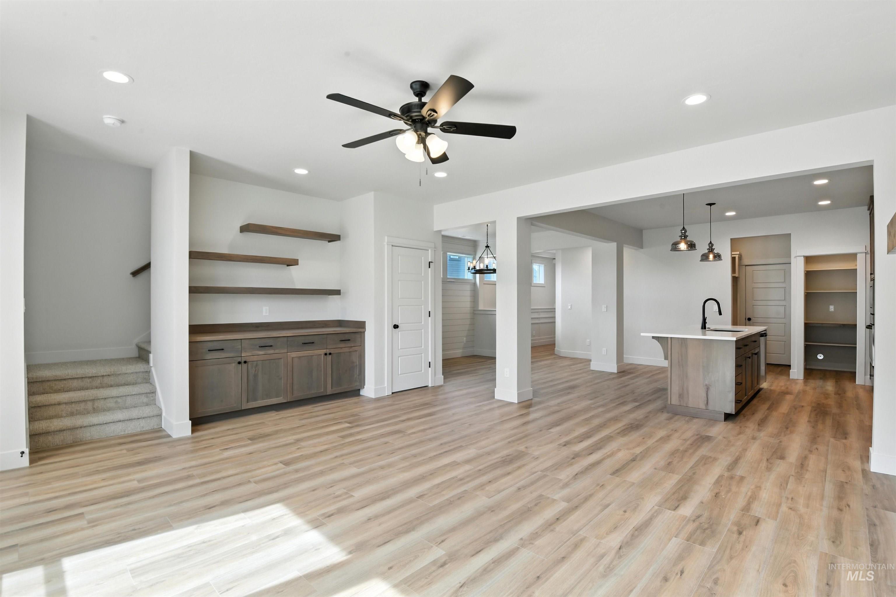 Unfurnished living room with stairway, light wood-type flooring, recessed lighting, and a ceiling fan