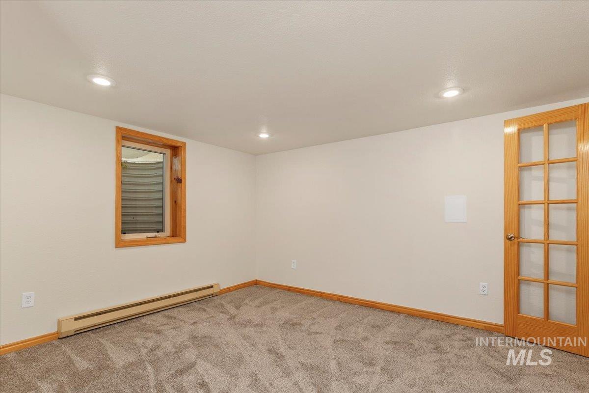 Unfurnished room featuring a baseboard radiator, light carpet, and recessed lighting