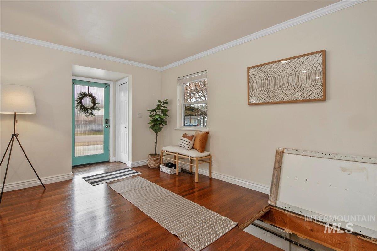 Foyer entrance with wood finished floors and crown molding