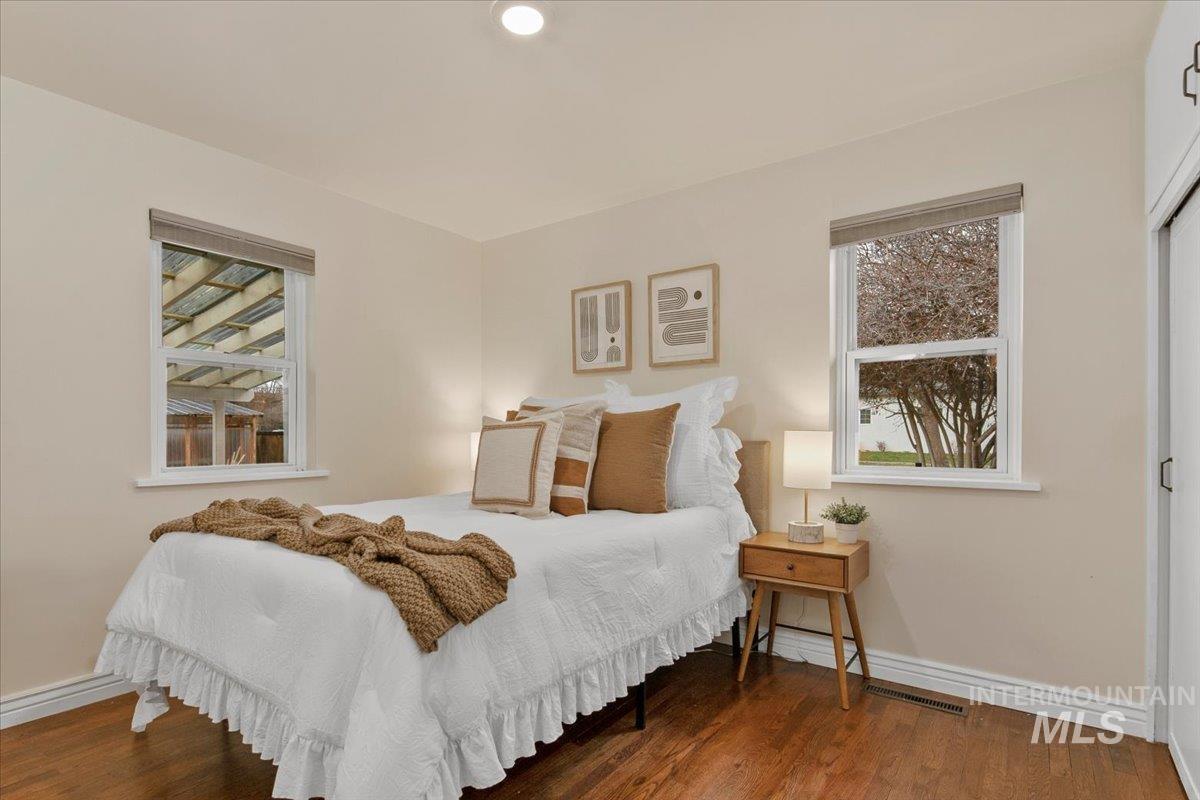 Bedroom with wood finished floors, multiple windows, and a closet