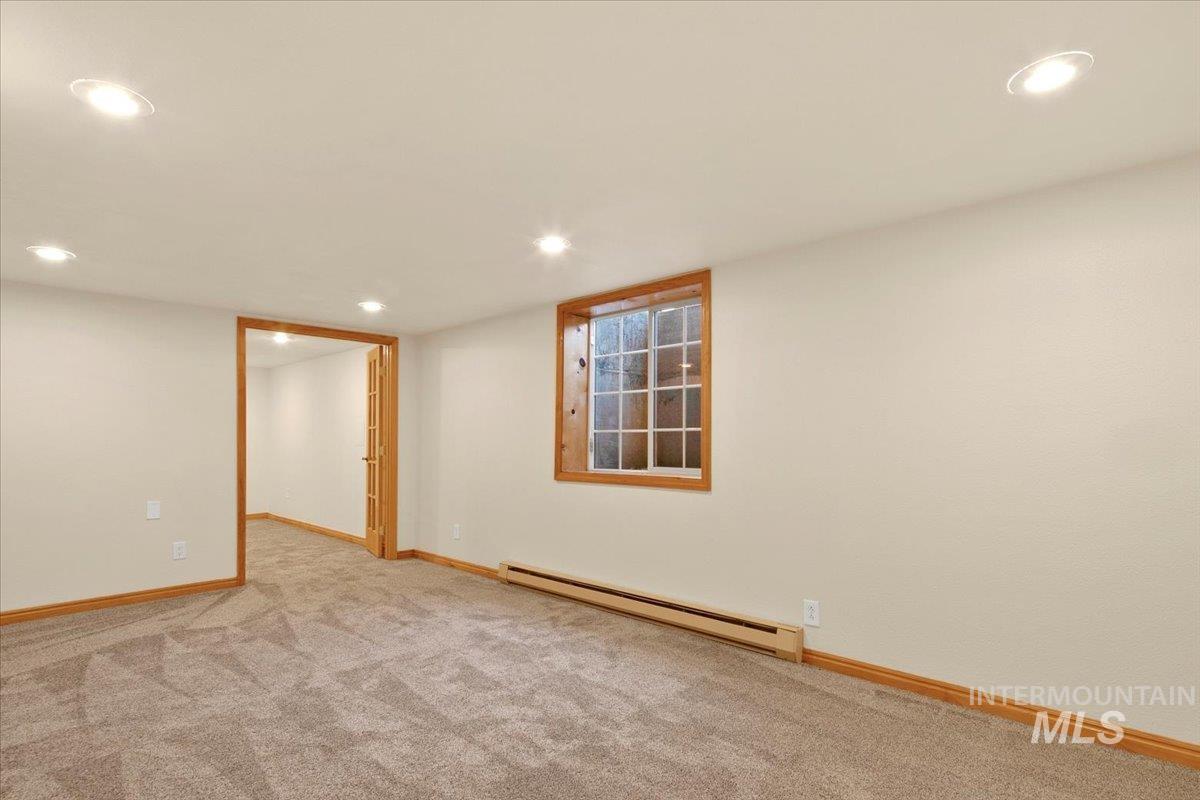 Empty room with a baseboard heating unit, recessed lighting, and light colored carpet