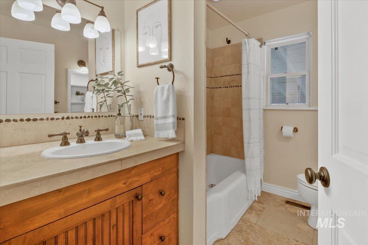 Bathroom with vanity, shower / bathtub combination with curtain, and tasteful backsplash