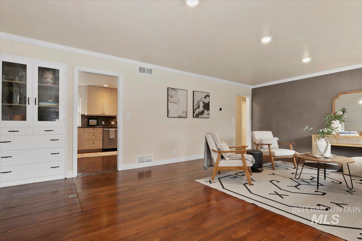 Sitting room featuring crown molding, dark wood-style flooring, recessed lighting, and an accent wall