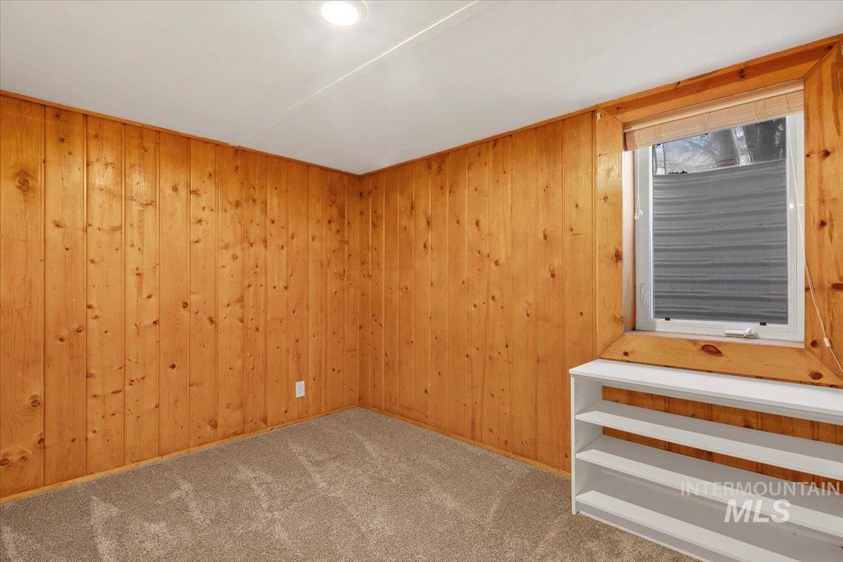 Carpeted spare room with wood walls