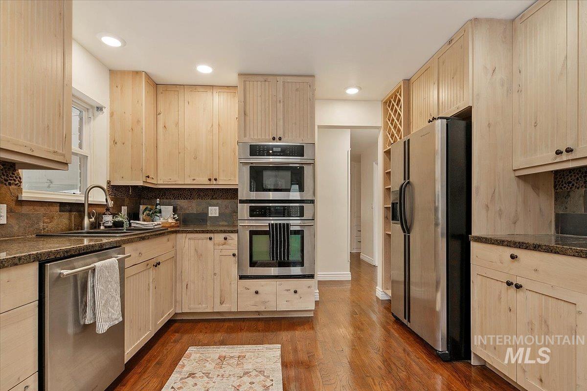 Kitchen with light brown cabinets, stainless steel appliances, tasteful backsplash, dark wood-style floors, and recessed lighting