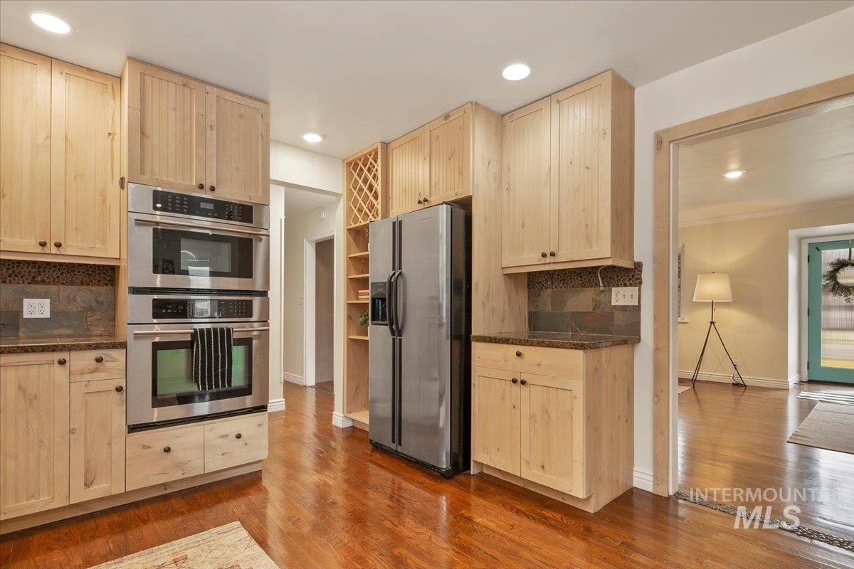 Kitchen with light brown cabinetry, backsplash, stainless steel appliances, light wood-type flooring, and recessed lighting