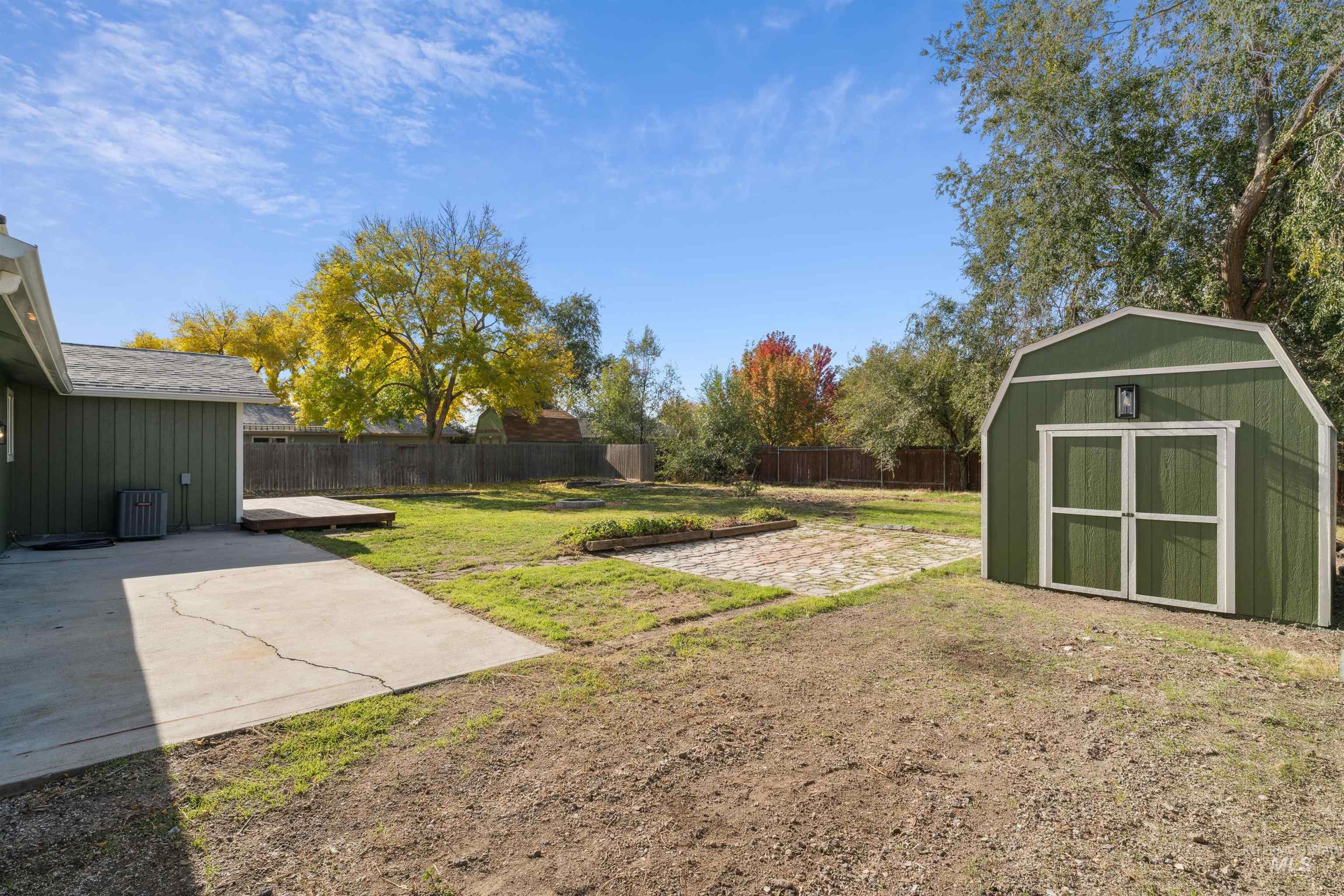 Fenced backyard with a patio area and a storage unit