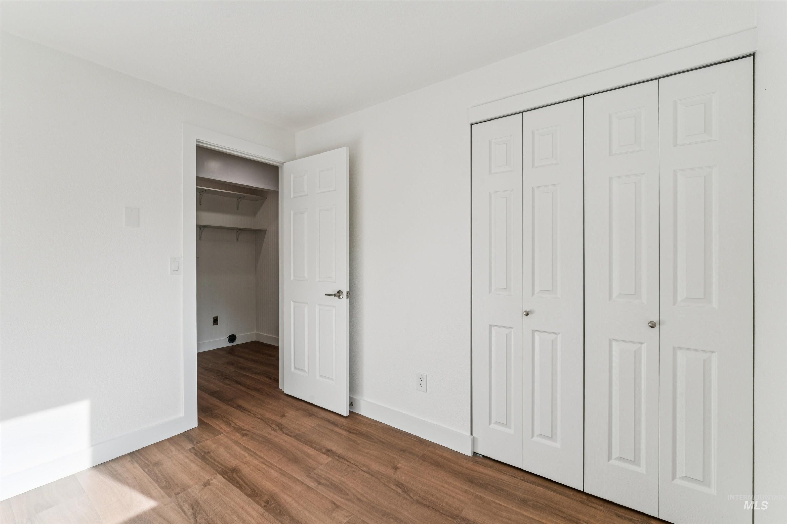 Unfurnished bedroom featuring a closet and dark wood-style floors