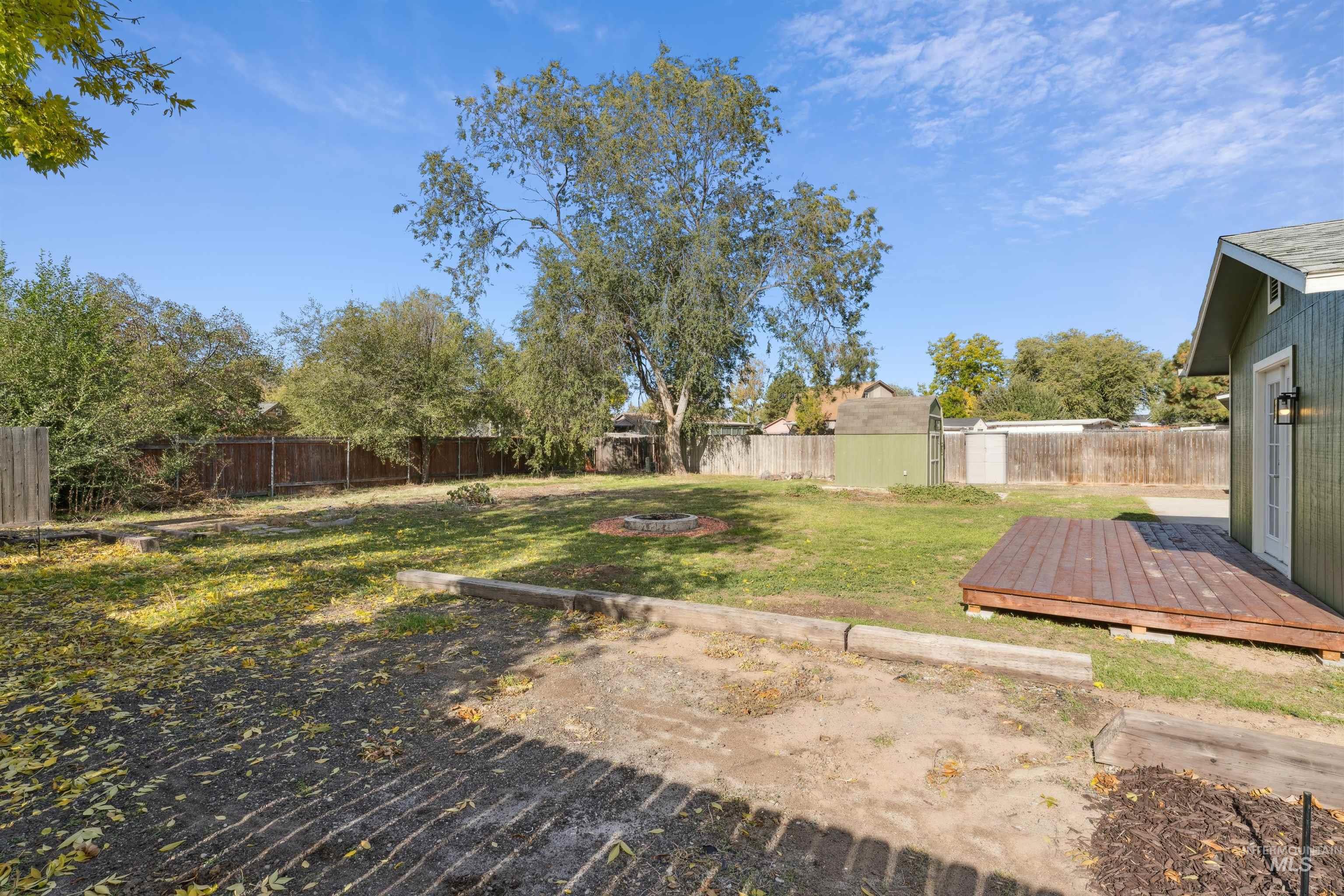 Fenced backyard featuring a deck and a fire pit