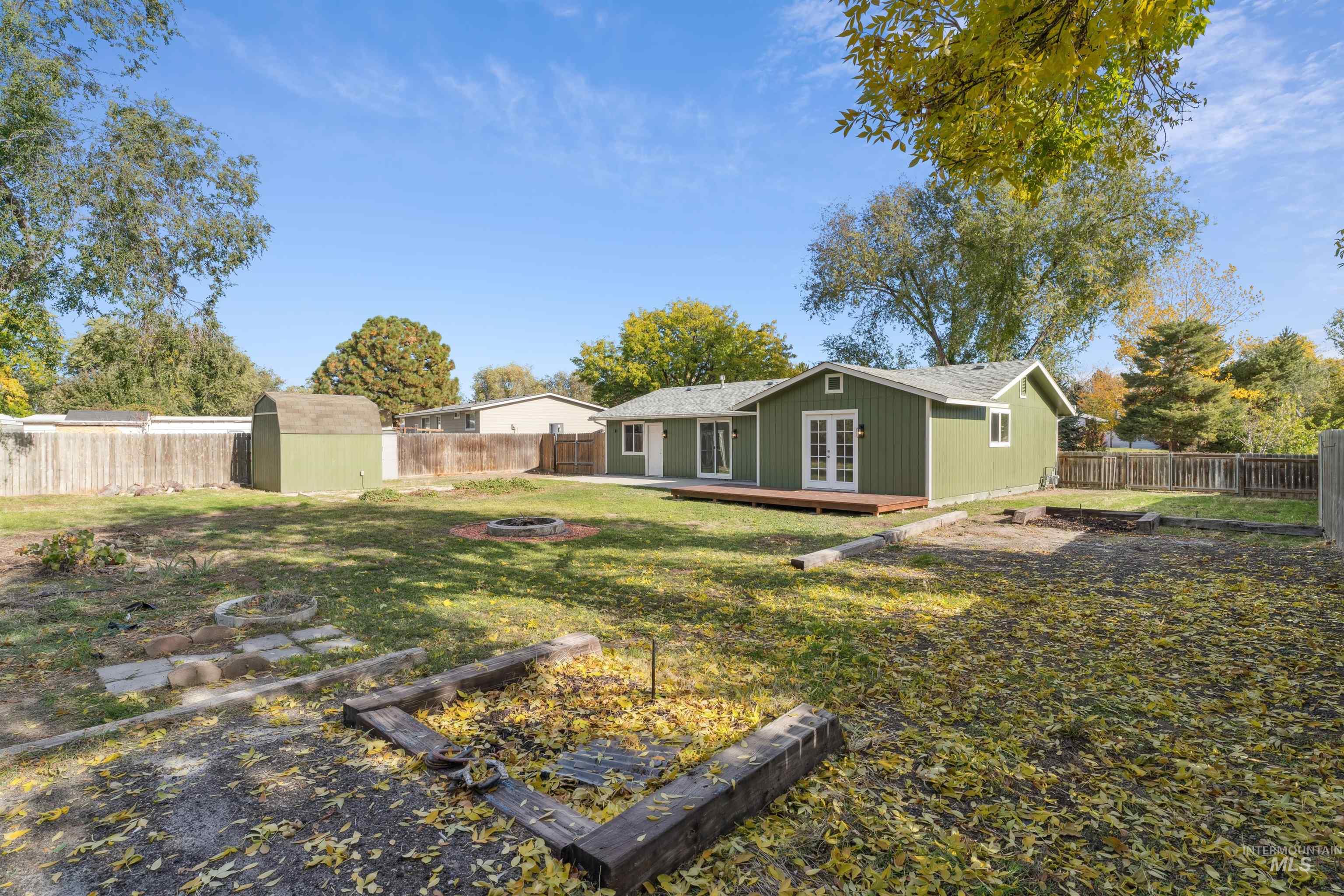 Fenced backyard with an outdoor fire pit, a shed, a wooden deck, and french doors