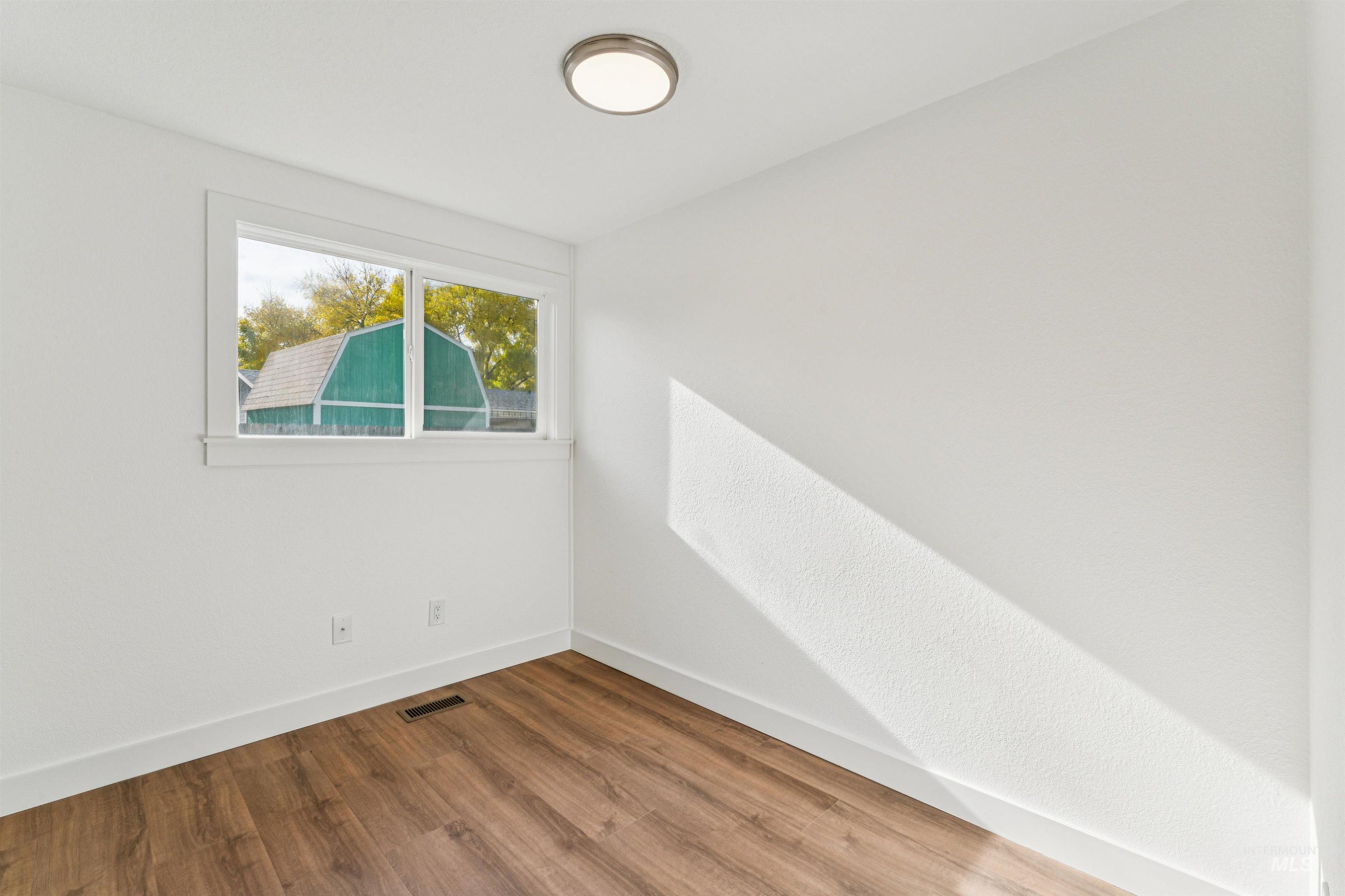 Unfurnished room featuring wood finished floors and baseboards