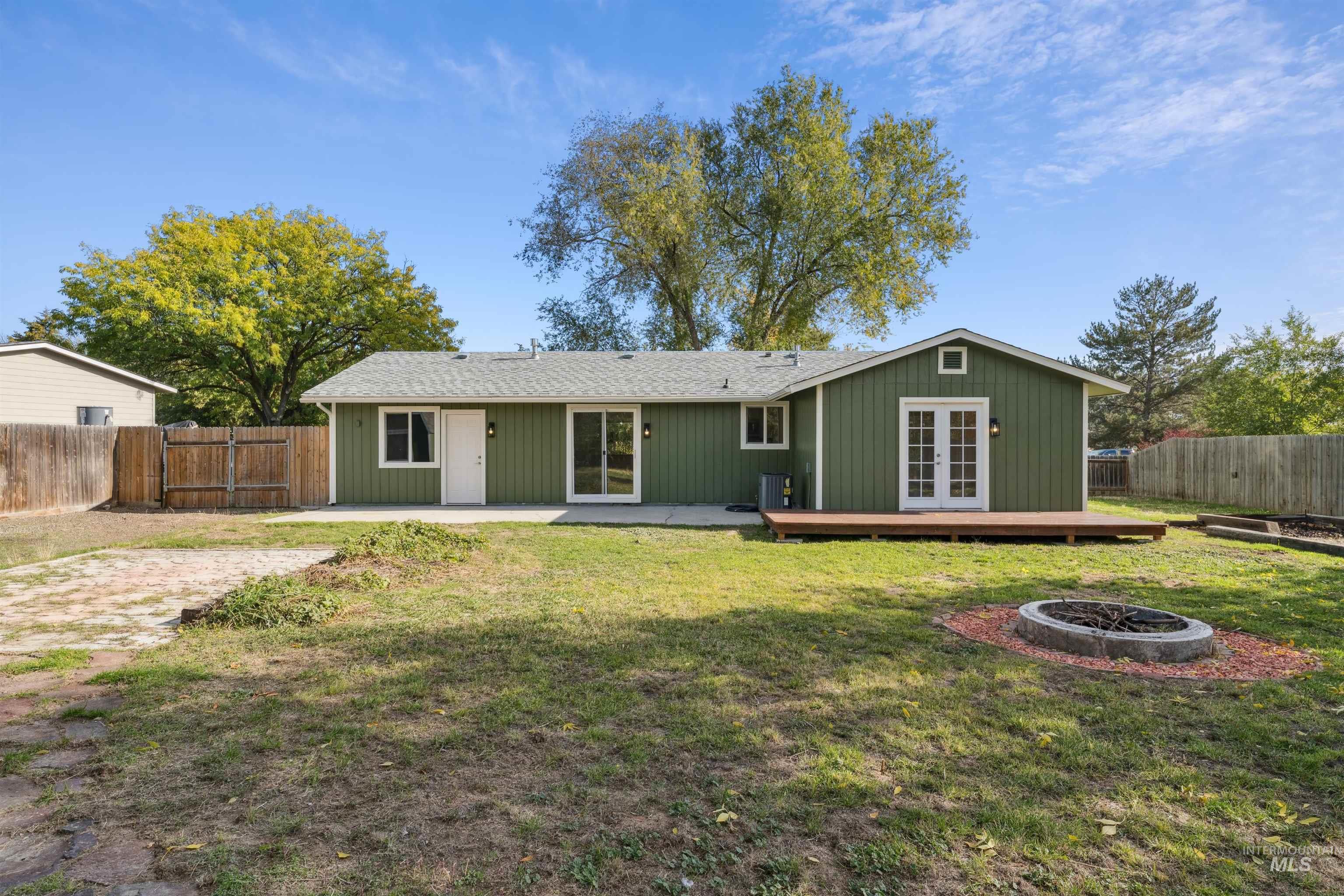 Rear view of property featuring a fenced backyard, an outdoor fire pit, french doors, and roof with shingles