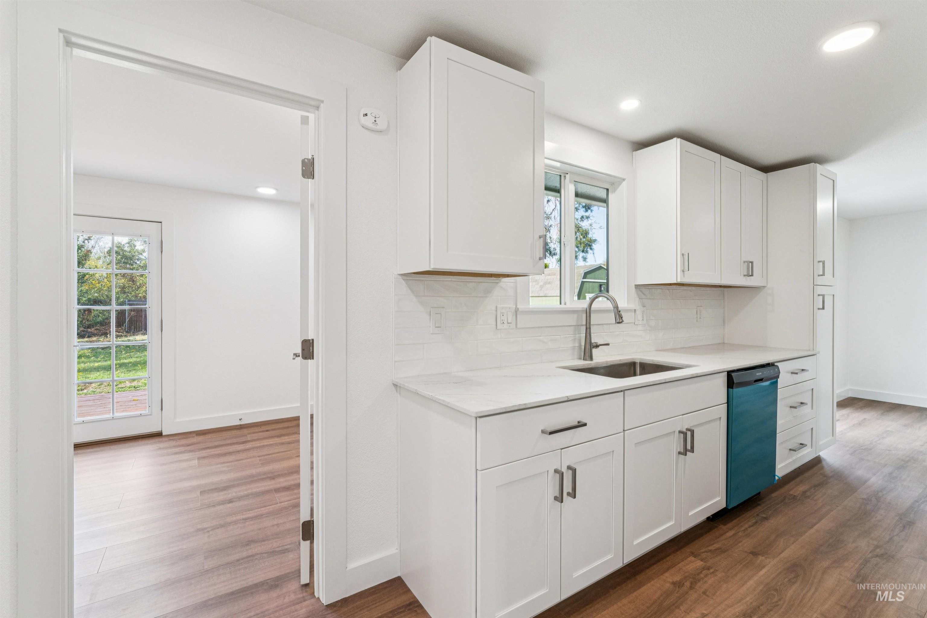 Kitchen featuring dark wood-style flooring, white cabinetry, recessed lighting, backsplash, and dishwasher
