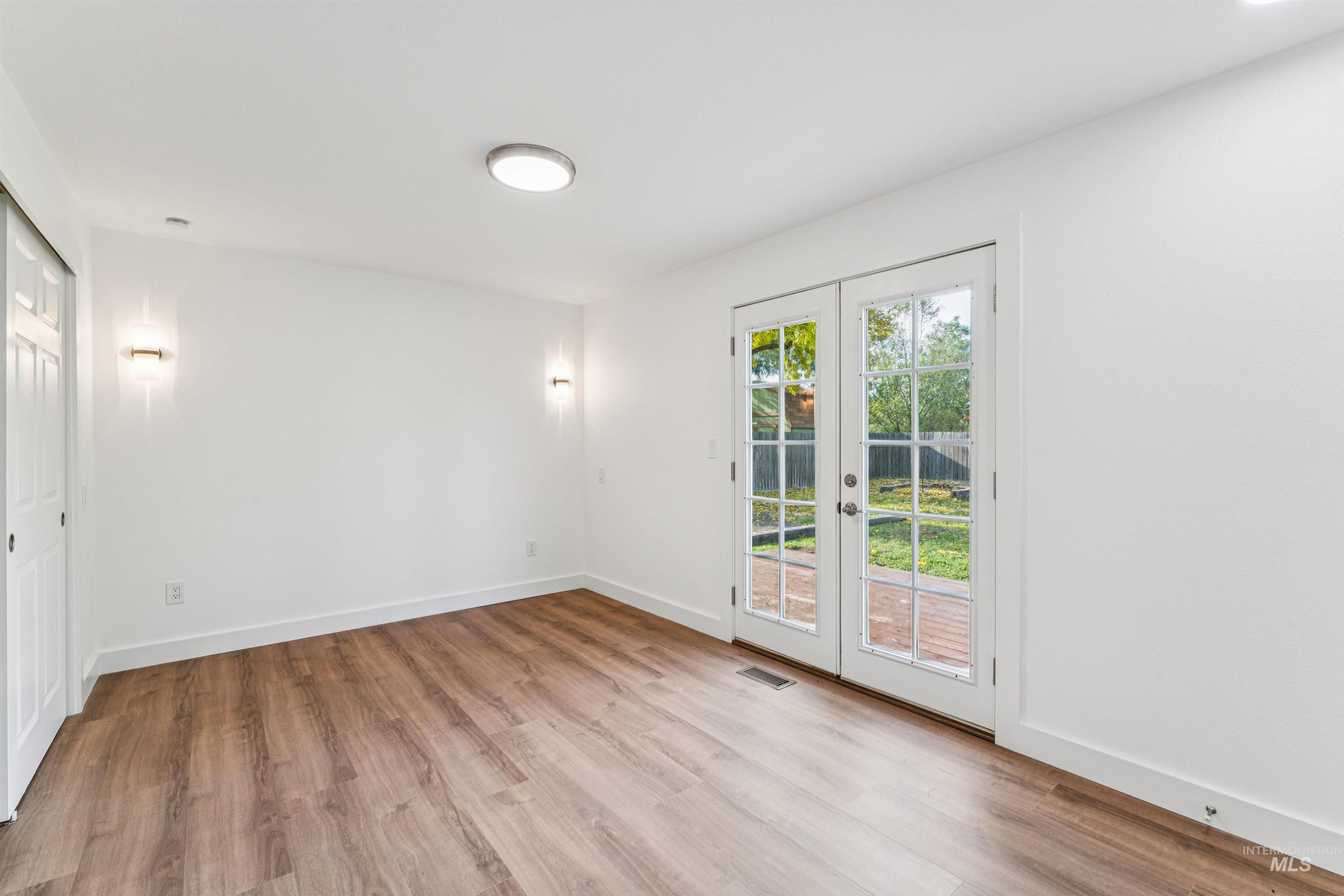 Unfurnished room with light wood-style floors and french doors