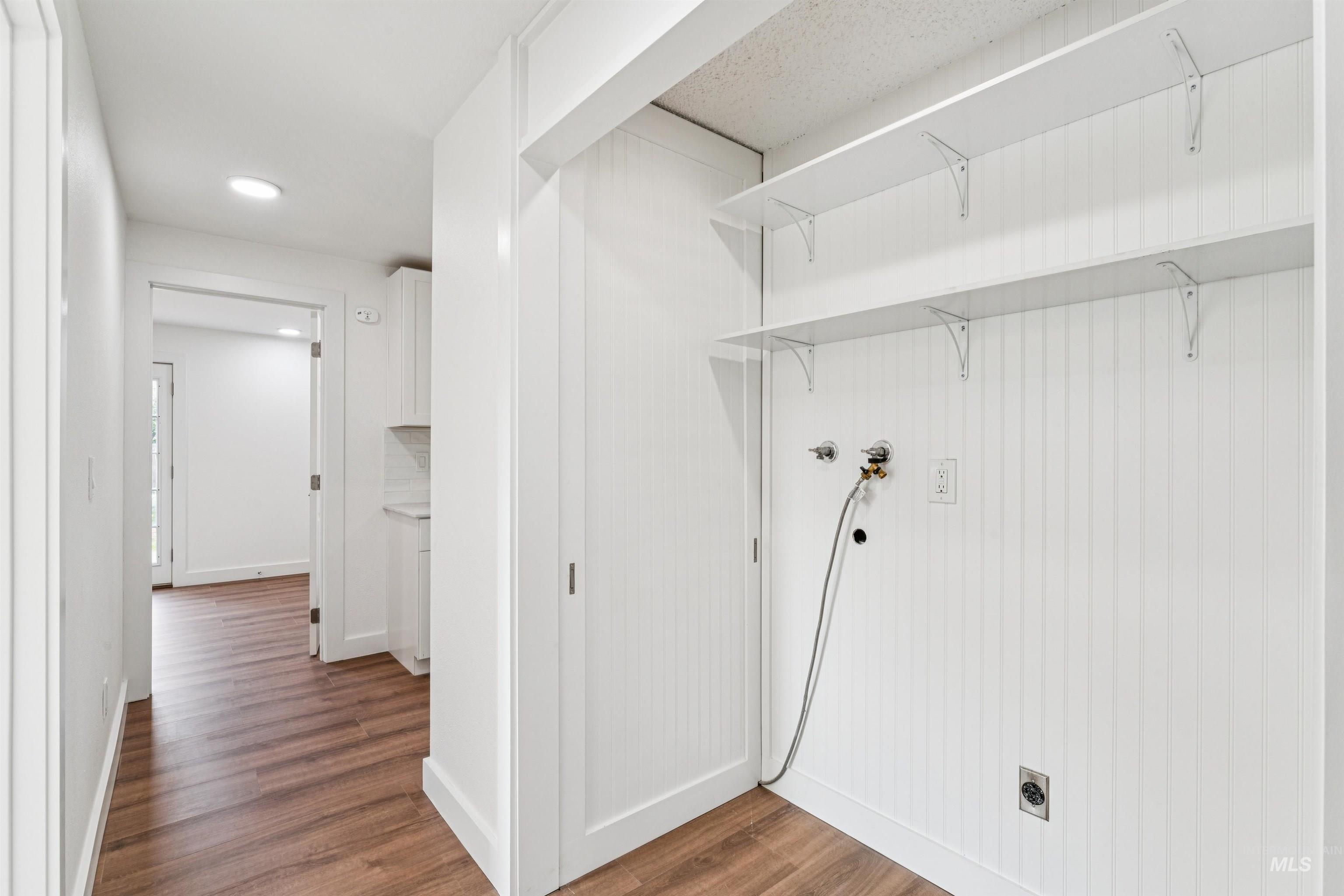 Washroom with dark wood-type flooring and hookup for a washing machine