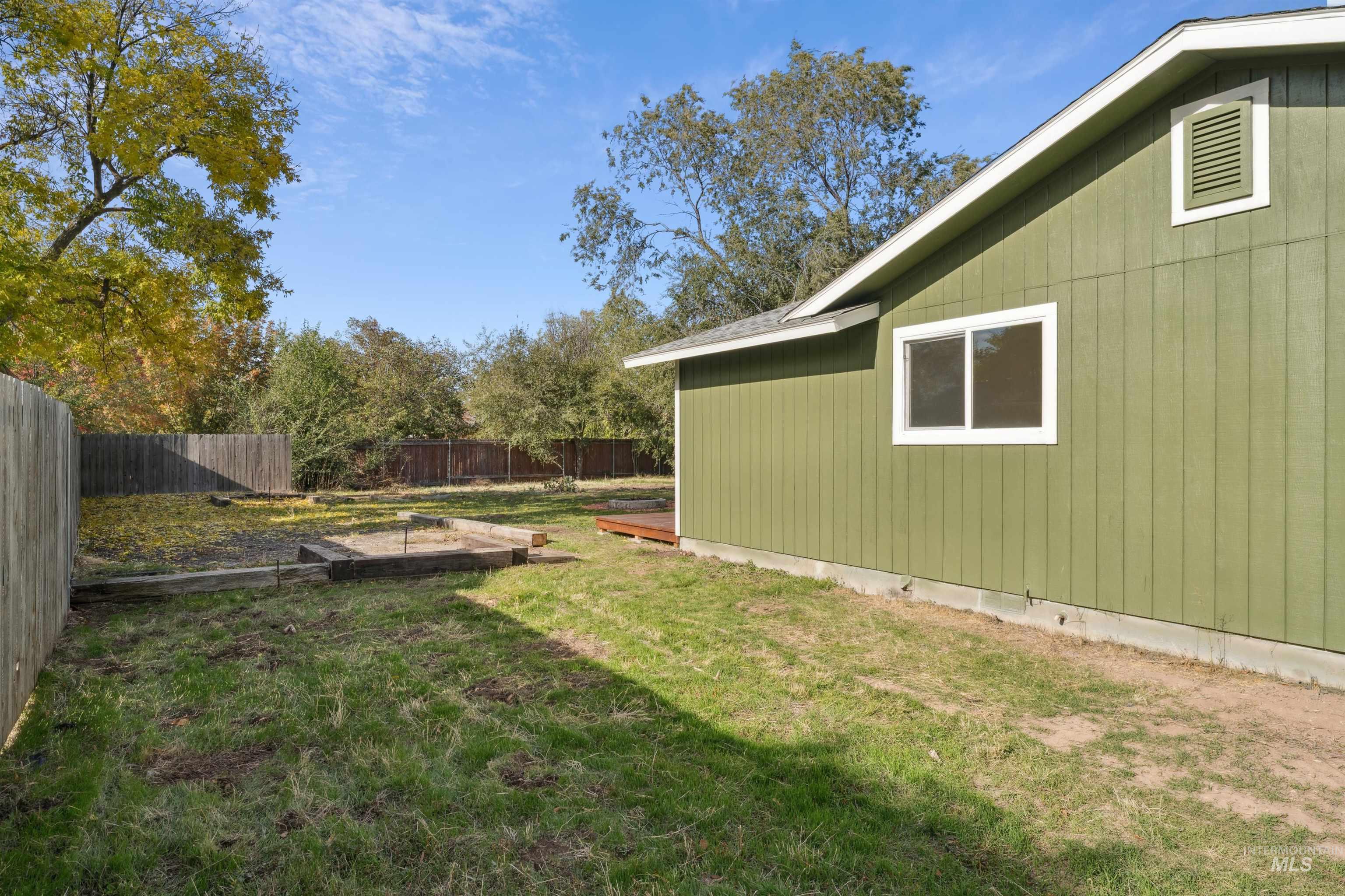 Fenced backyard with a vegetable garden and a deck