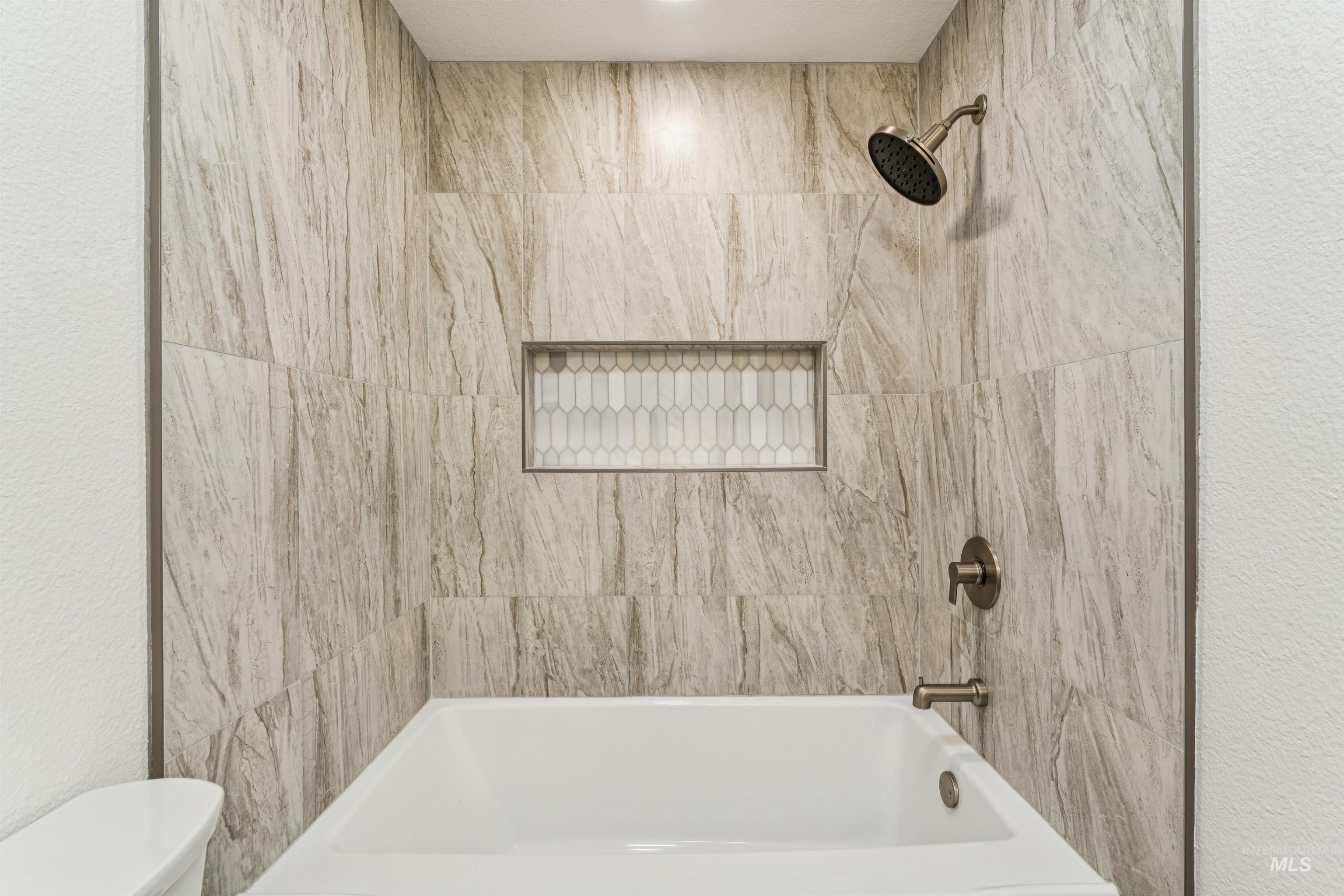 Bathroom featuring bathtub / shower combination and a textured wall