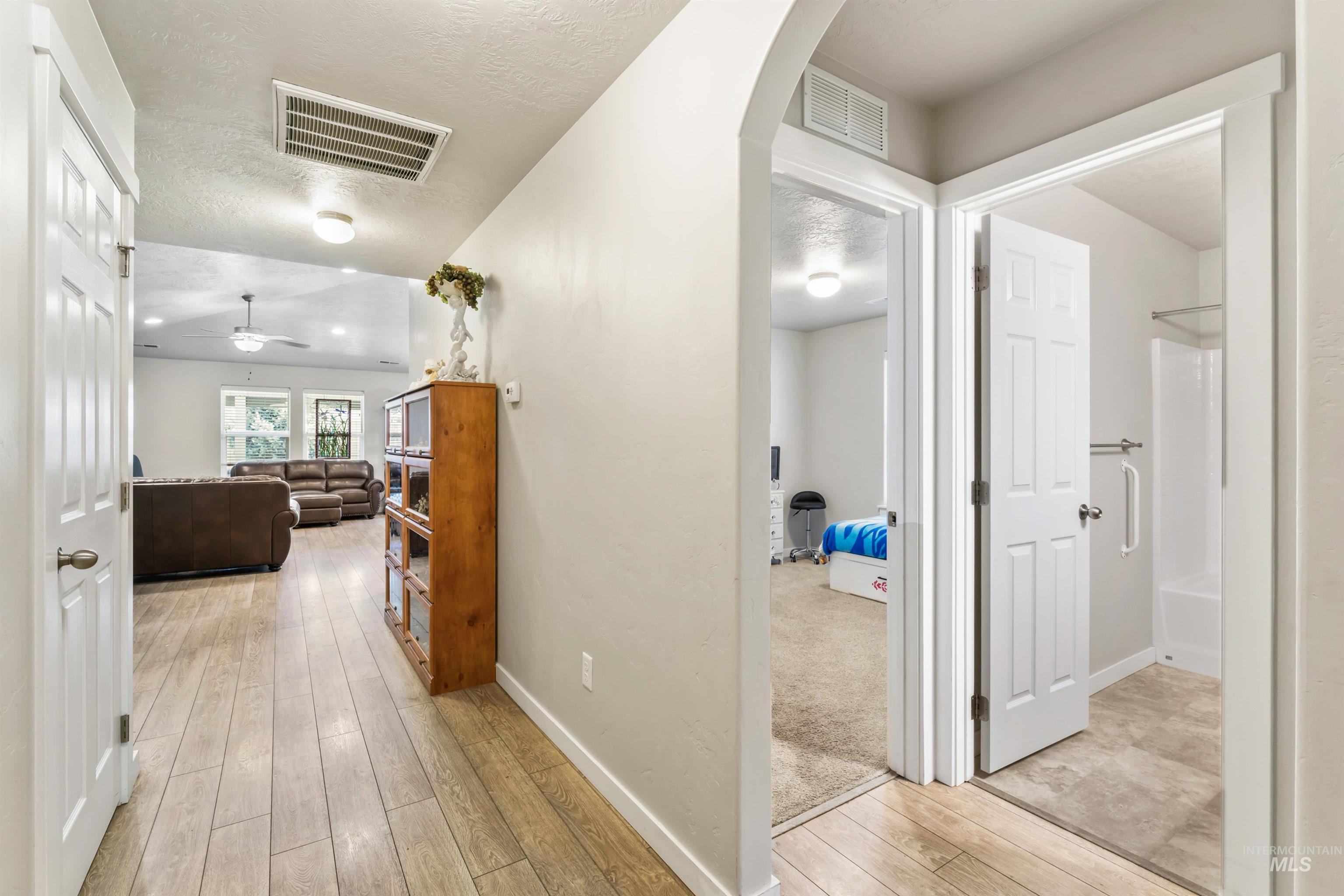 Hall featuring light wood finished floors, arched walkways, and a textured ceiling