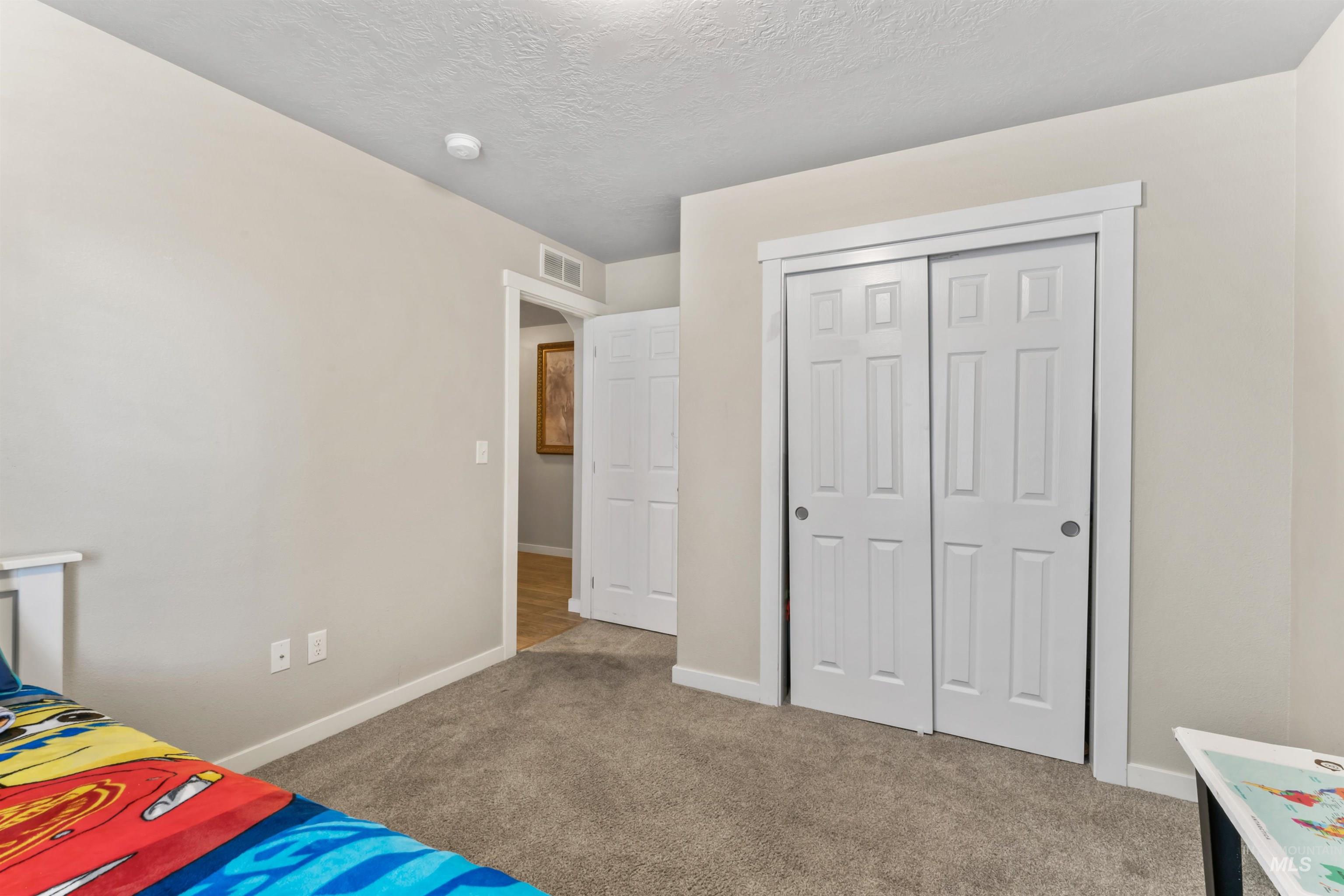 Bedroom featuring carpet, a textured ceiling, and a closet