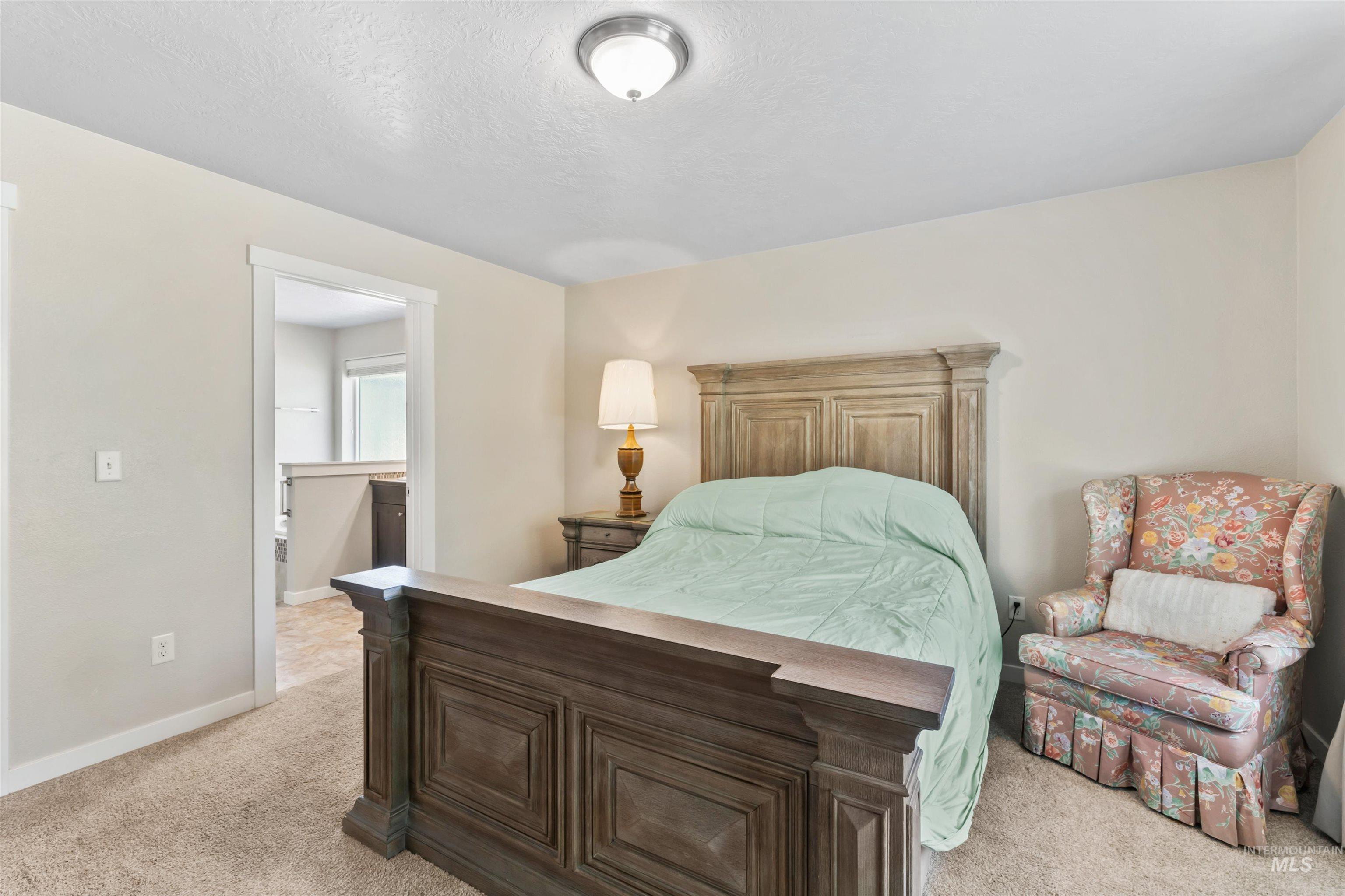 Bedroom with light carpet, connected bathroom, and a textured ceiling