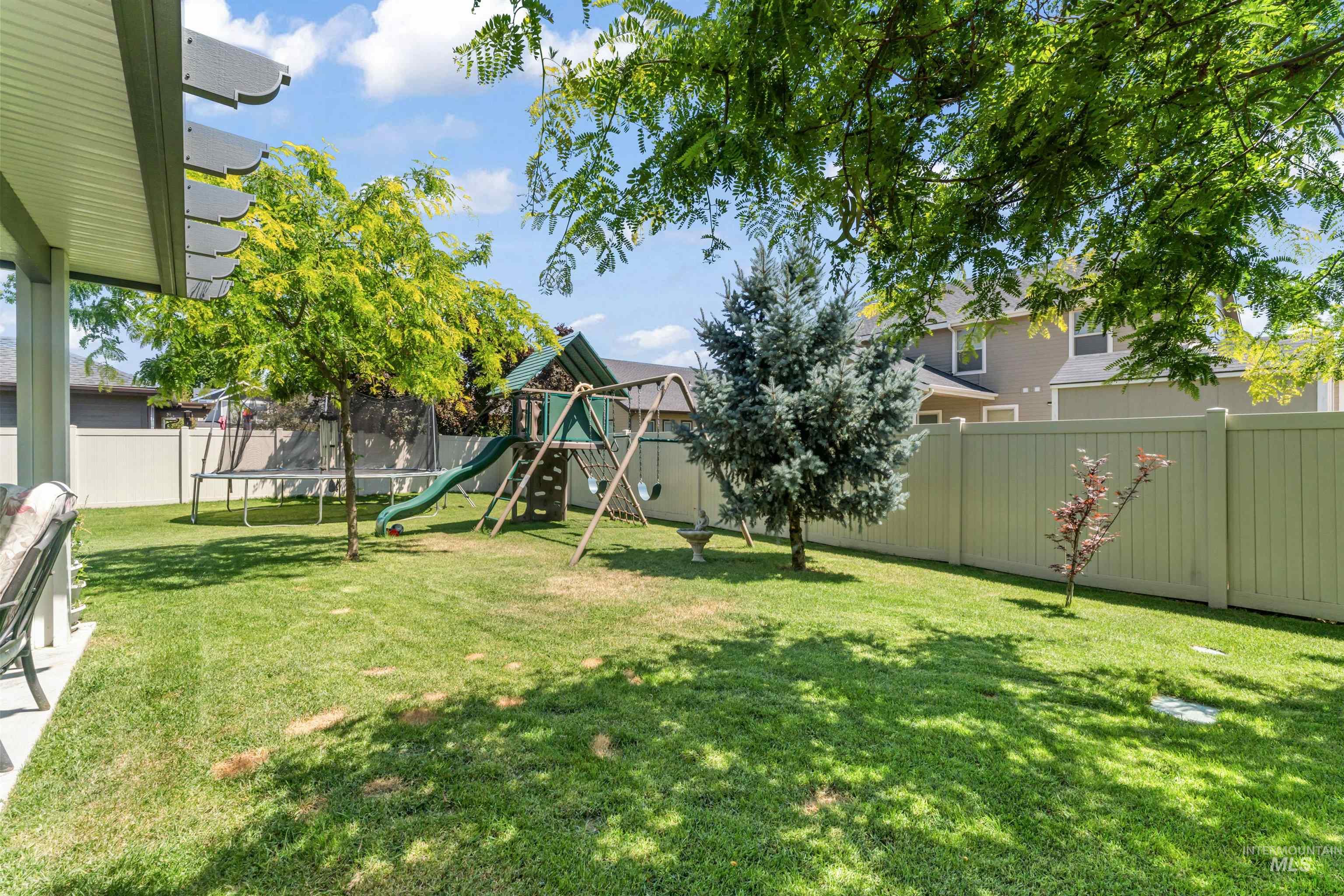 Fenced backyard with a trampoline and a playground