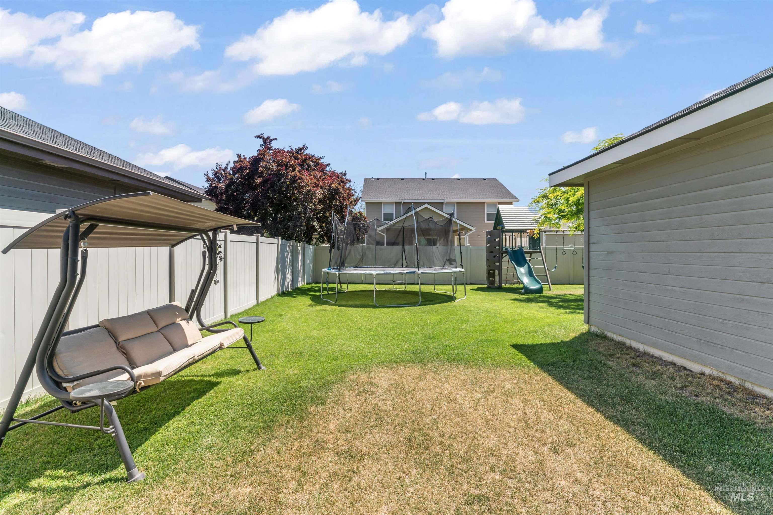 Fenced backyard with a trampoline and a playground