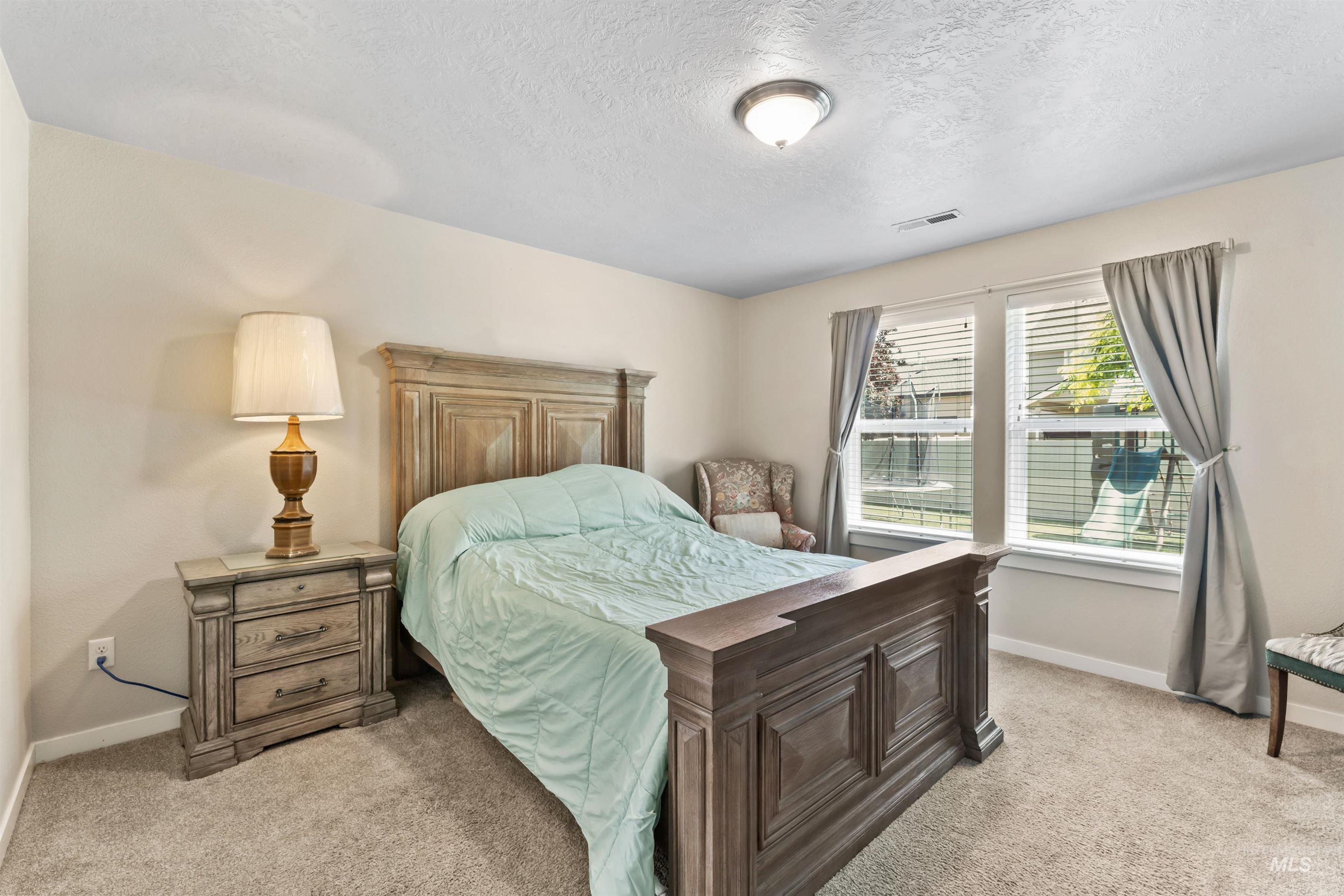 Bedroom with light carpet and a textured ceiling