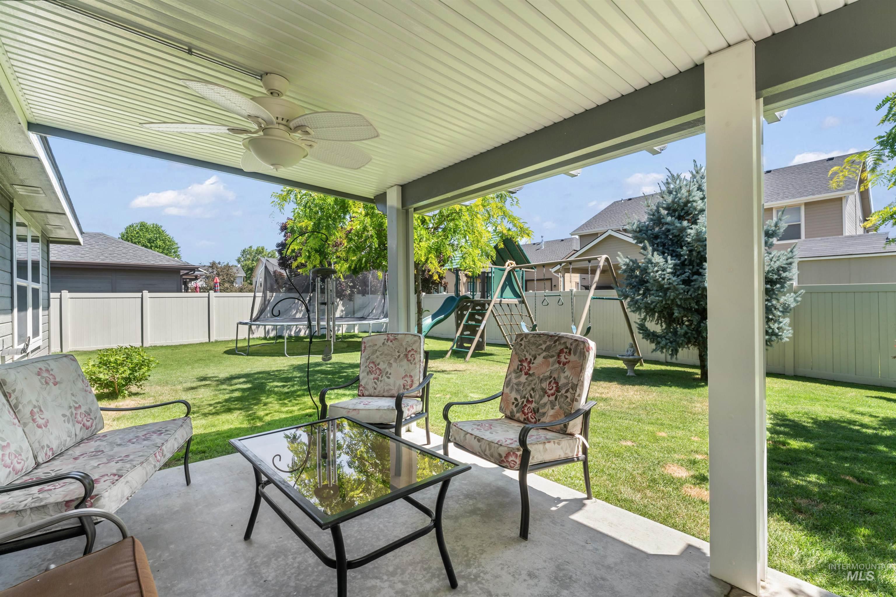 Fenced backyard featuring a trampoline, a playground, a patio area, an outdoor living space, and ceiling fan
