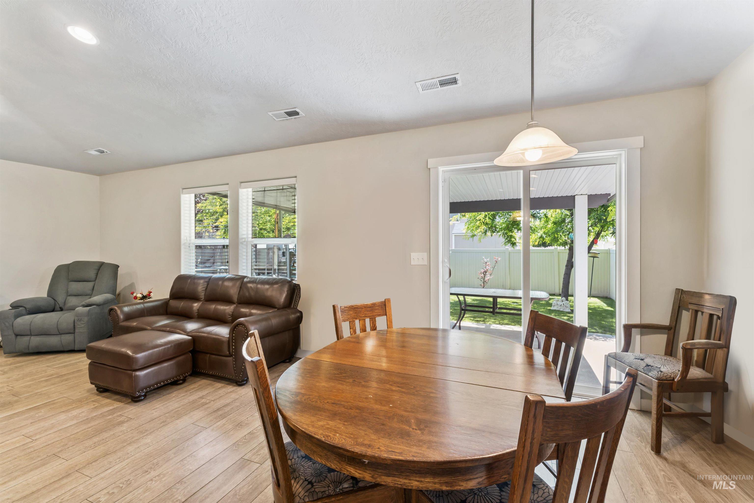 Dining space featuring light wood-type flooring, healthy amount of natural light, and a textured ceiling