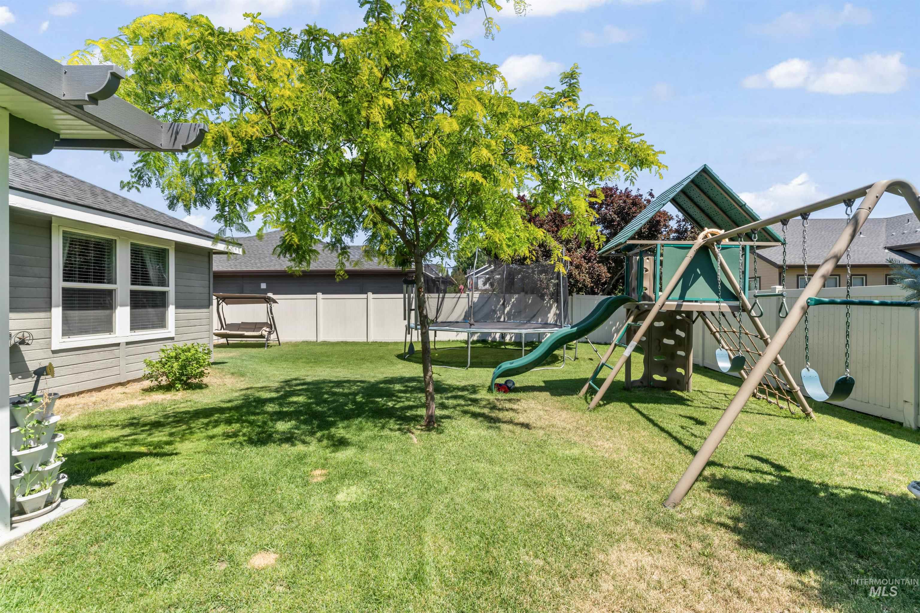 Fenced backyard with a trampoline and a playground