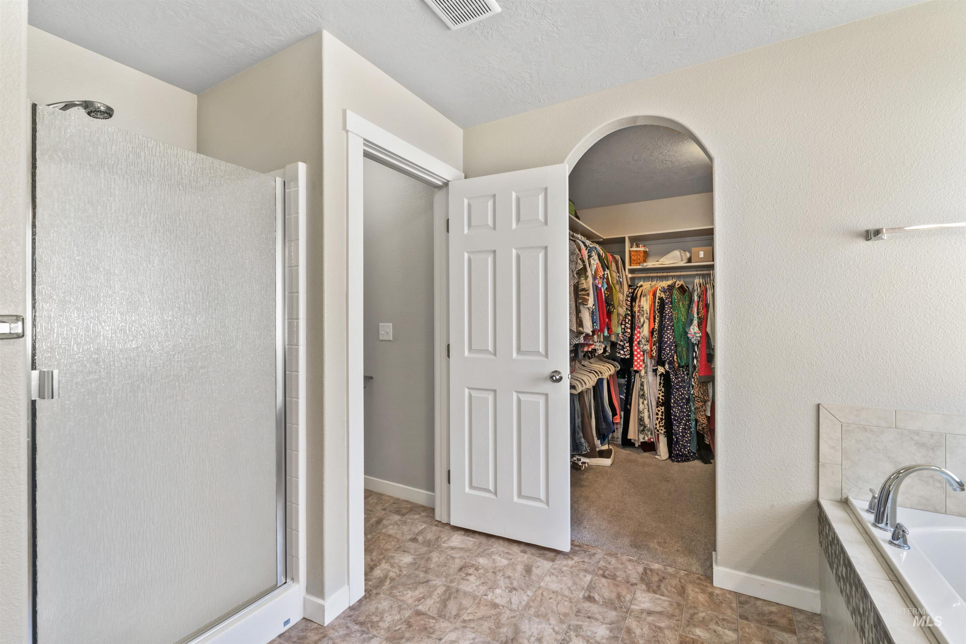 Bathroom with a shower stall, a bath, and a spacious closet