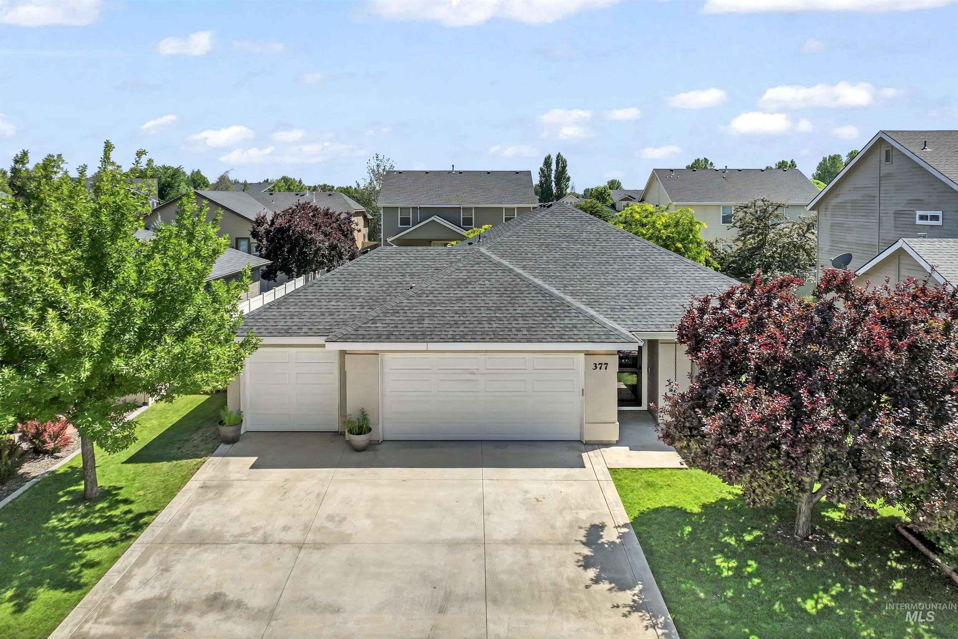 Traditional home featuring a garage, roof with shingles, driveway, and a front lawn