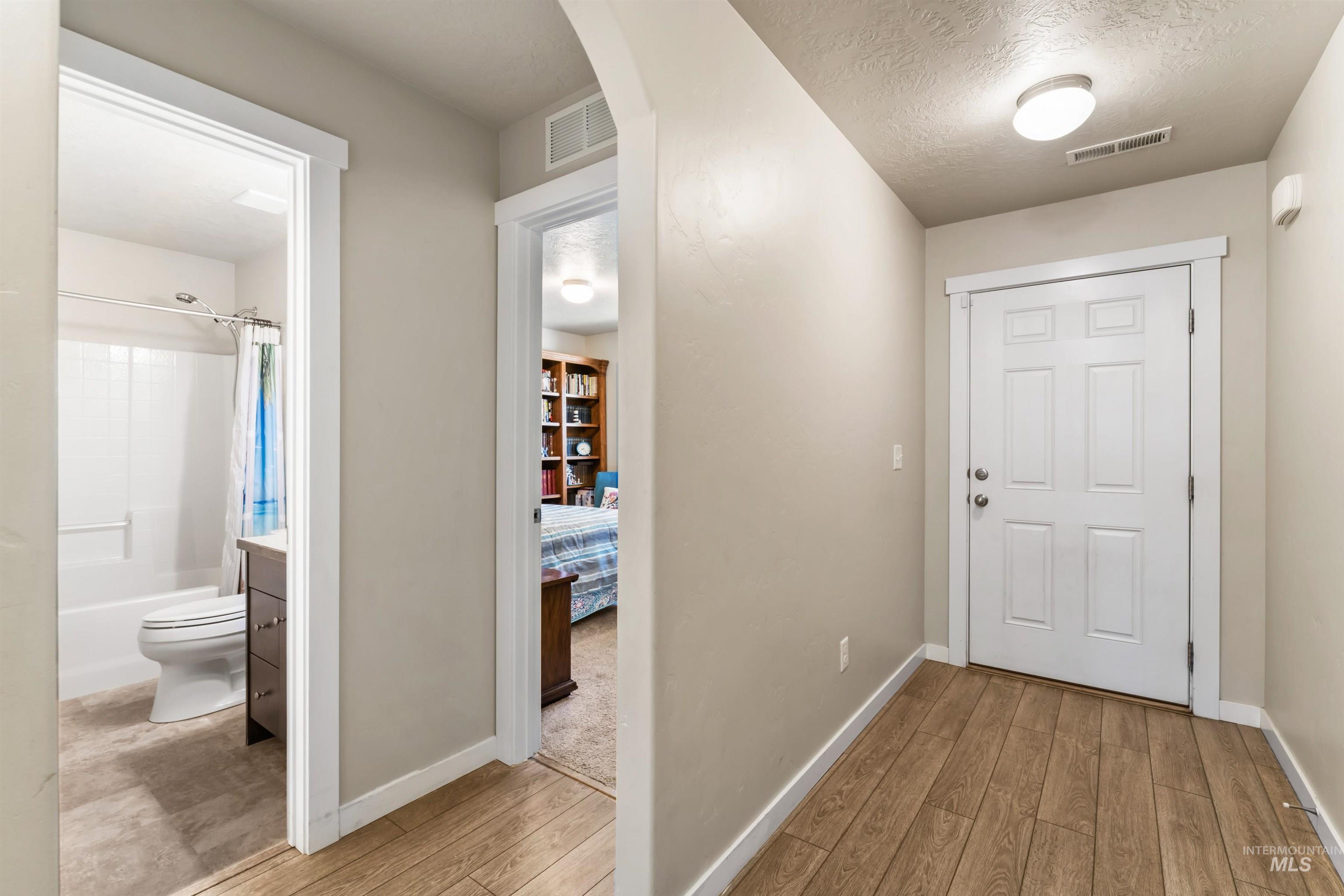 Corridor featuring wood finished floors, arched walkways, and a textured ceiling