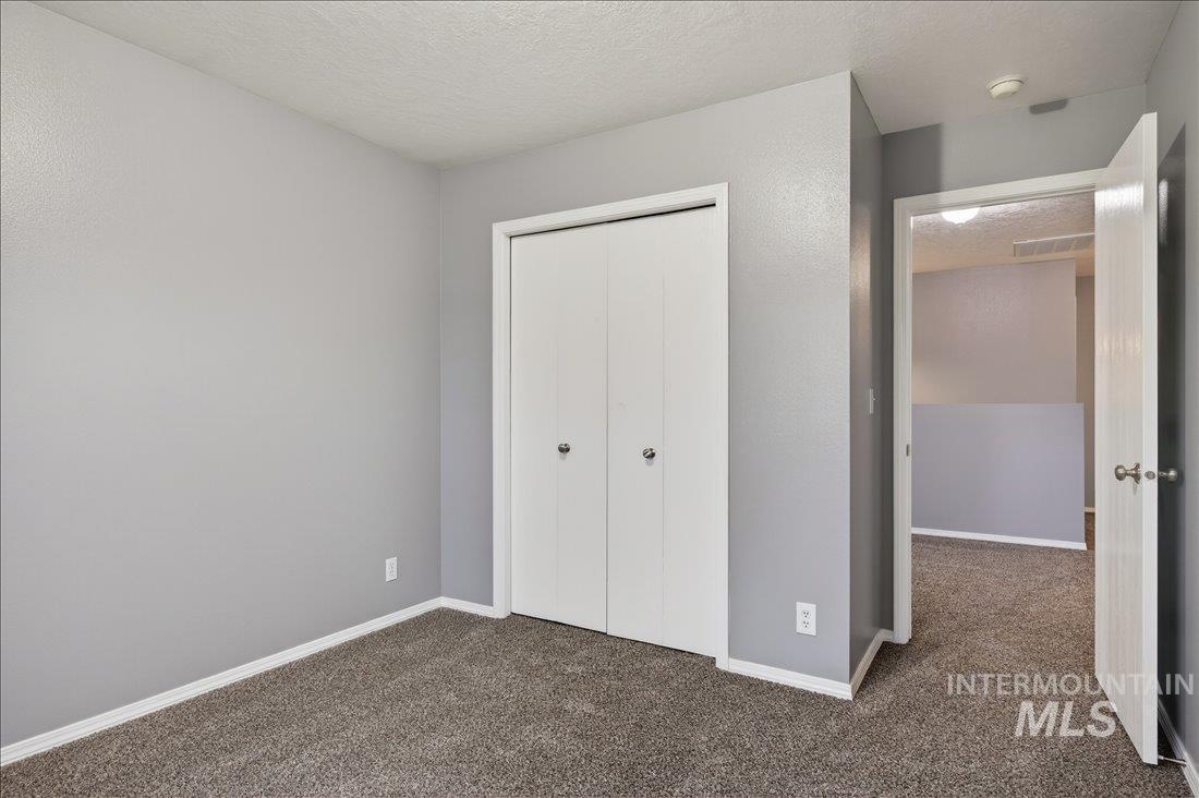 Unfurnished bedroom with carpet, a closet, and a textured ceiling