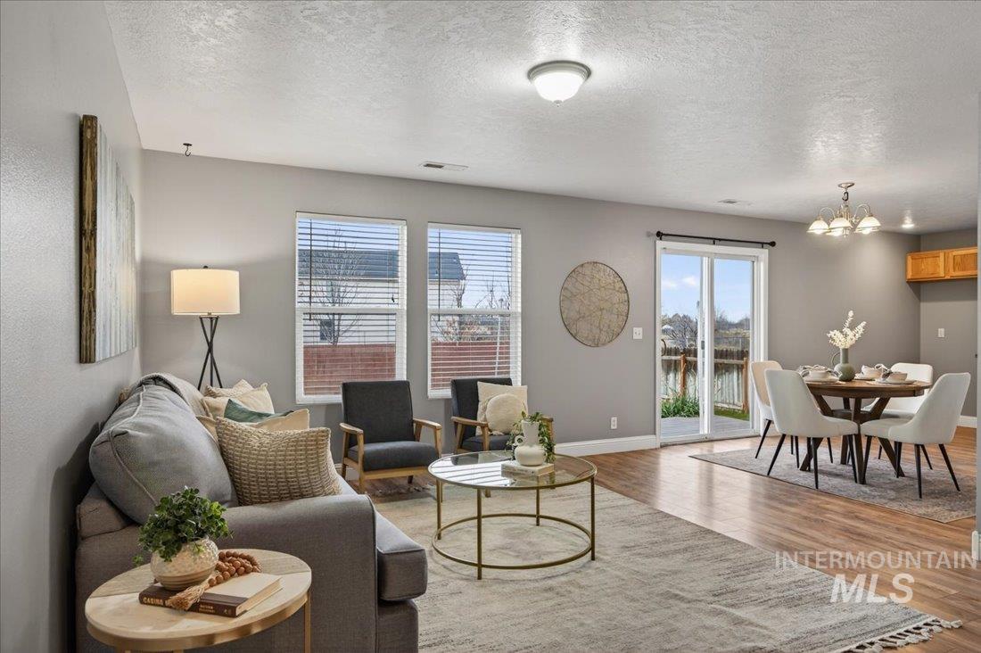 Living area featuring a textured ceiling, a water view, healthy amount of natural light, light wood-type flooring, and a chandelier