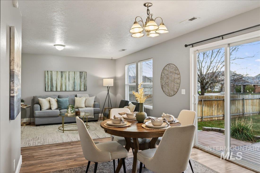 Dining space with a textured ceiling, a chandelier, and wood finished floors