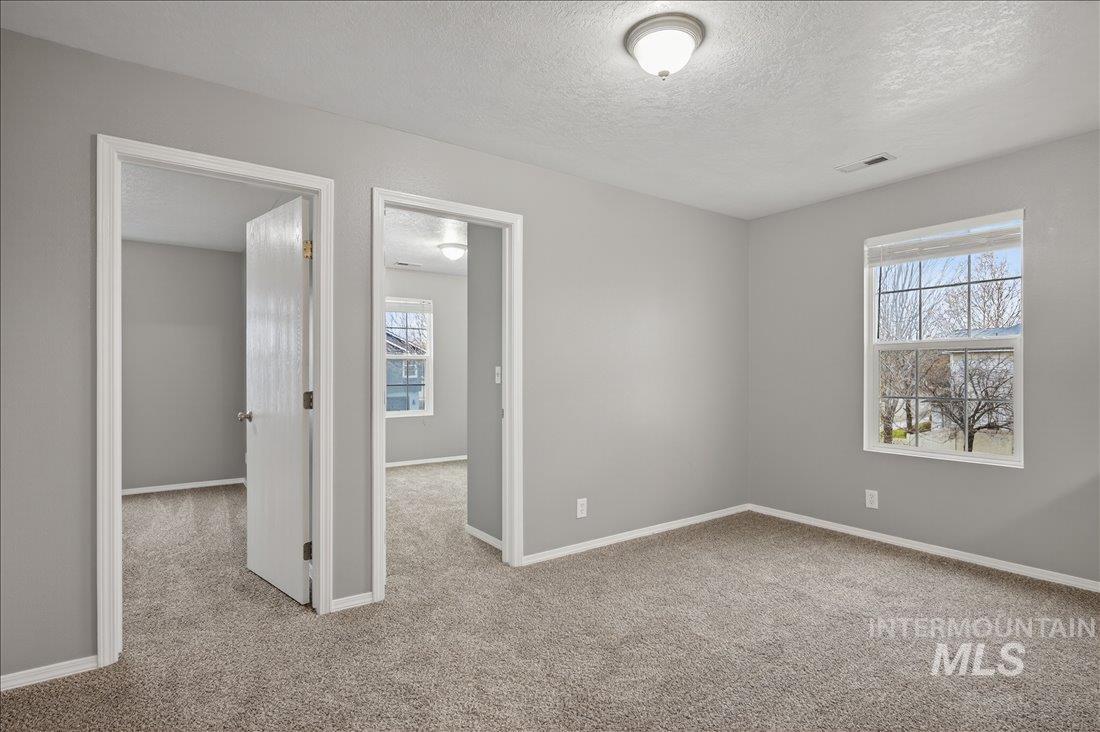 Empty room featuring a textured ceiling and light colored carpet