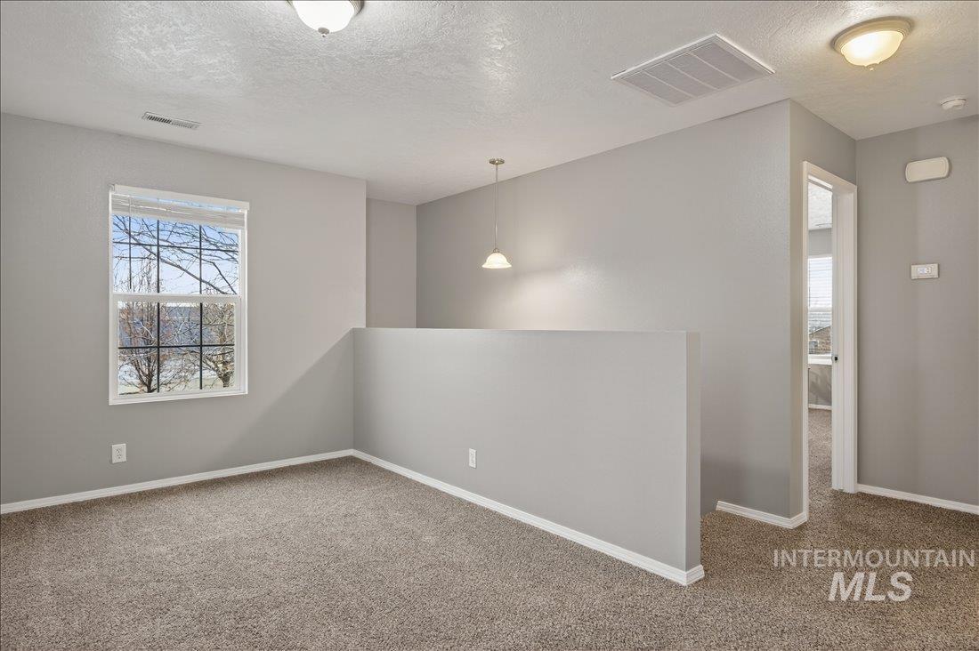 Unfurnished room featuring a textured ceiling and carpet flooring