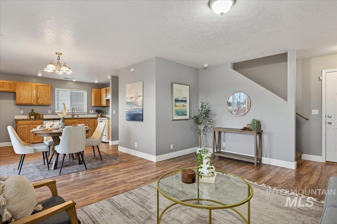 Living area with a textured ceiling, light wood finished floors, a chandelier, and stairway