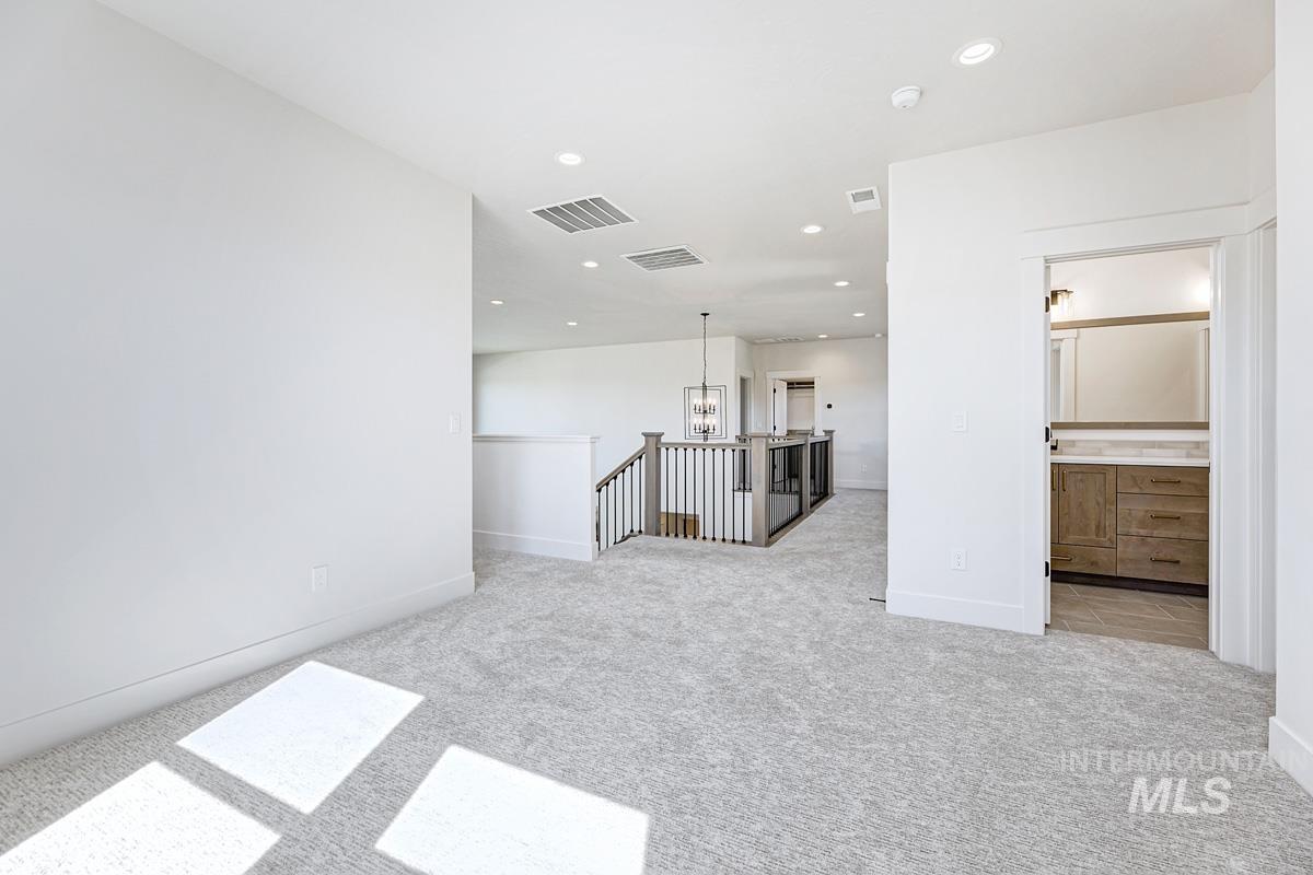 Unfurnished living room with recessed lighting, light carpet, and a chandelier