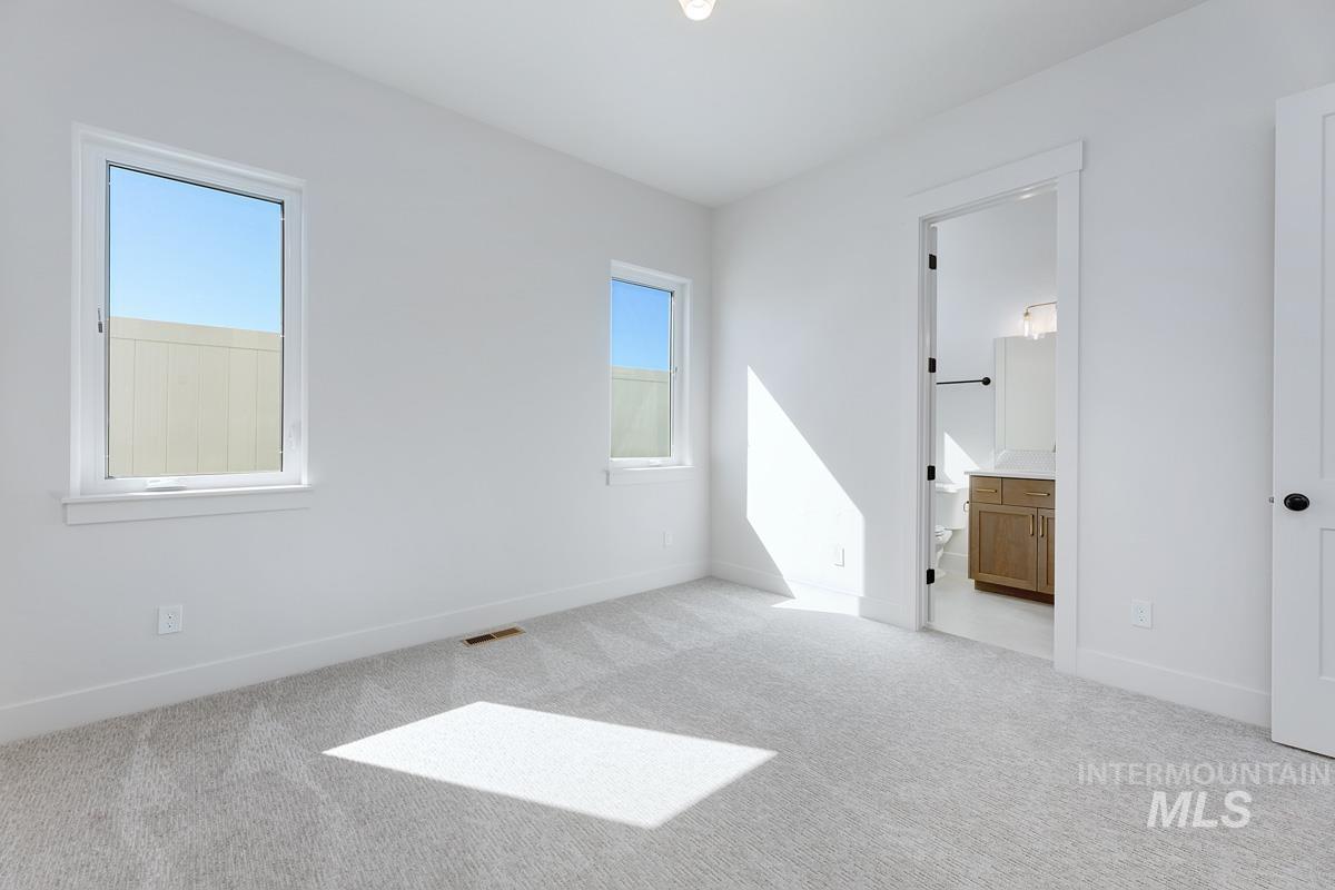 Unfurnished bedroom featuring light carpet and connected bathroom