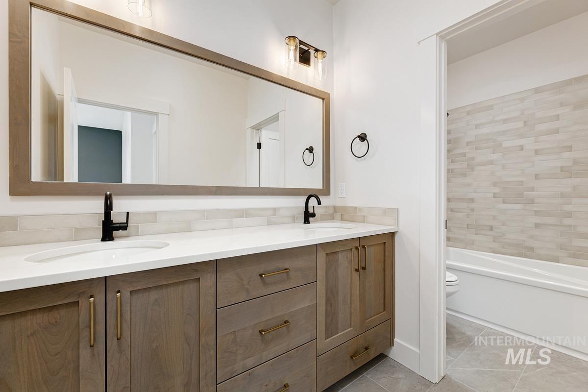 Full bathroom featuring double vanity, light tile patterned floors, and  shower combination