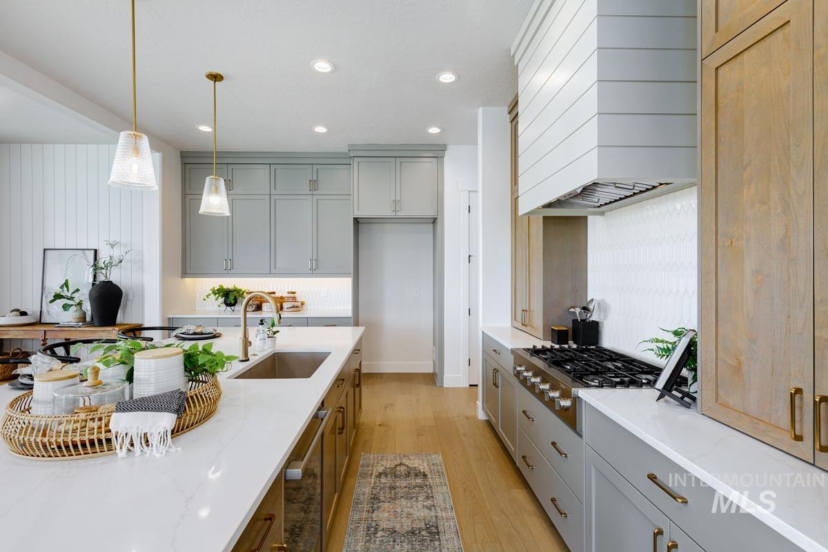 Kitchen with recessed lighting, pendant lighting, light wood-type flooring, custom range hood, and light stone counters