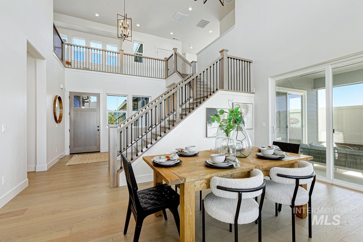 Dining space featuring light wood finished floors, a chandelier, a high ceiling, recessed lighting, and stairs