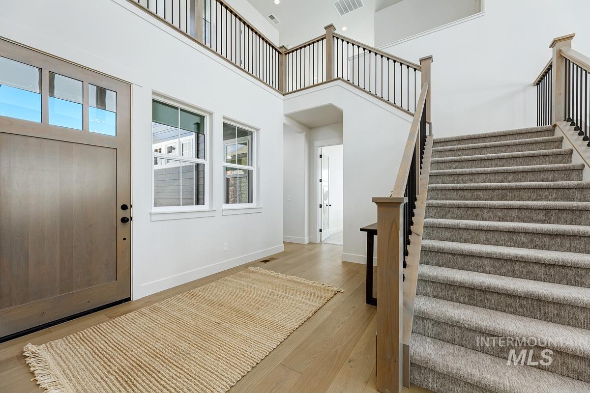 Entryway with light wood finished floors, a towering ceiling, and stairs