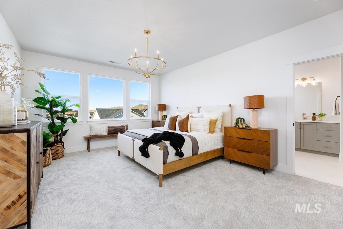 Bedroom with light carpet, ensuite bathroom, and a chandelier